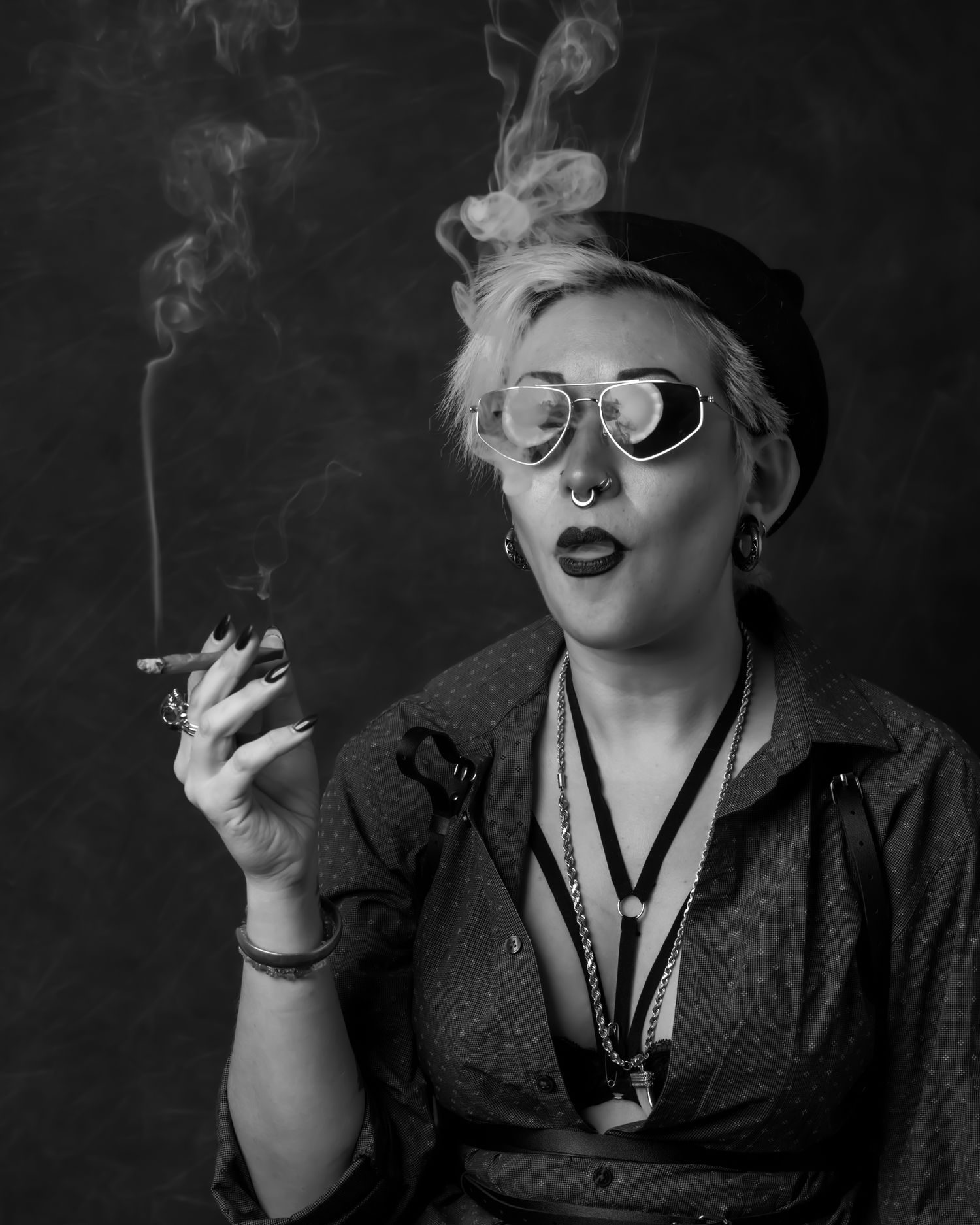 Dramatic black and white portrait of someone in vintage attire exhaling smoke.