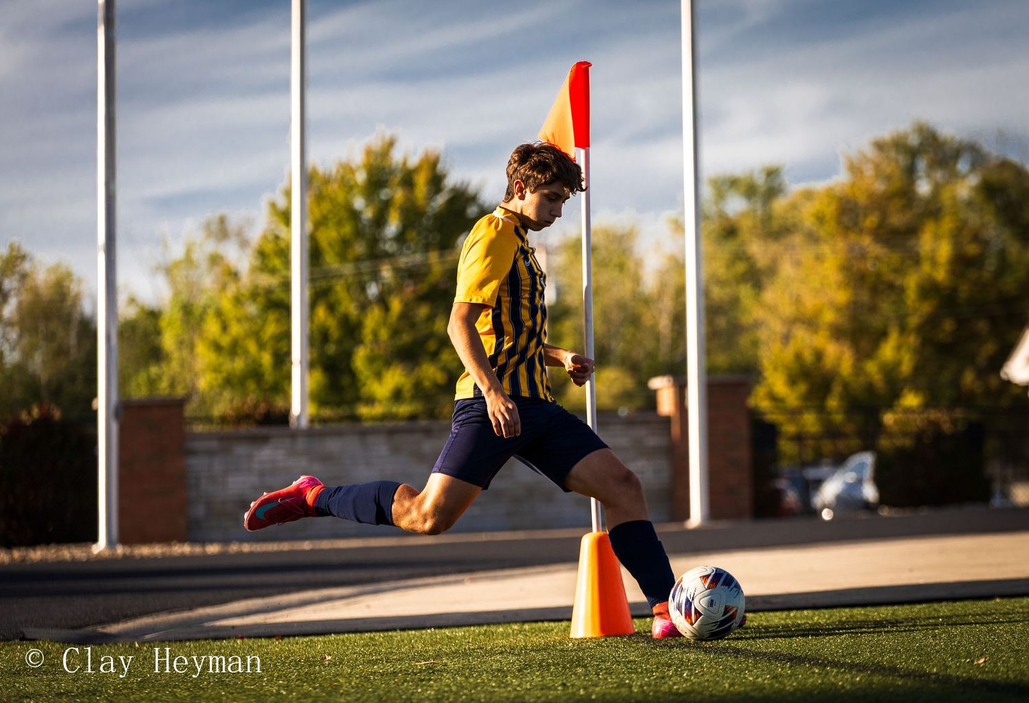 Young soccer player practicing dribbling around cones on outdoor turf field.