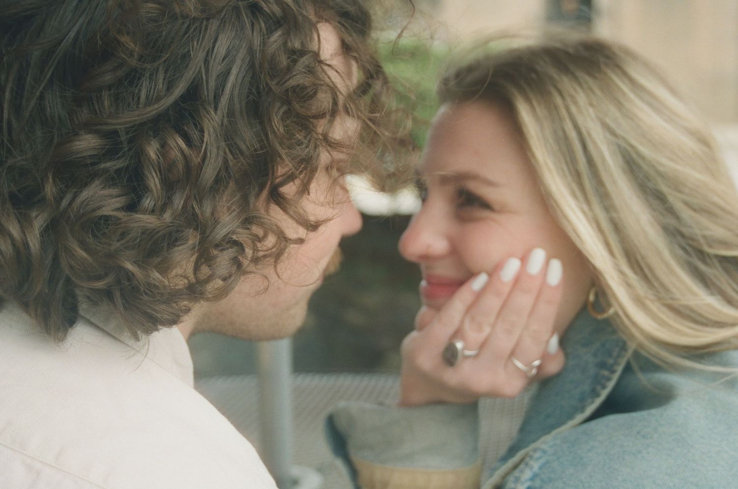 Romantic close-up of couple nearly kissing, woman smiling and showing diamond engagement ring.