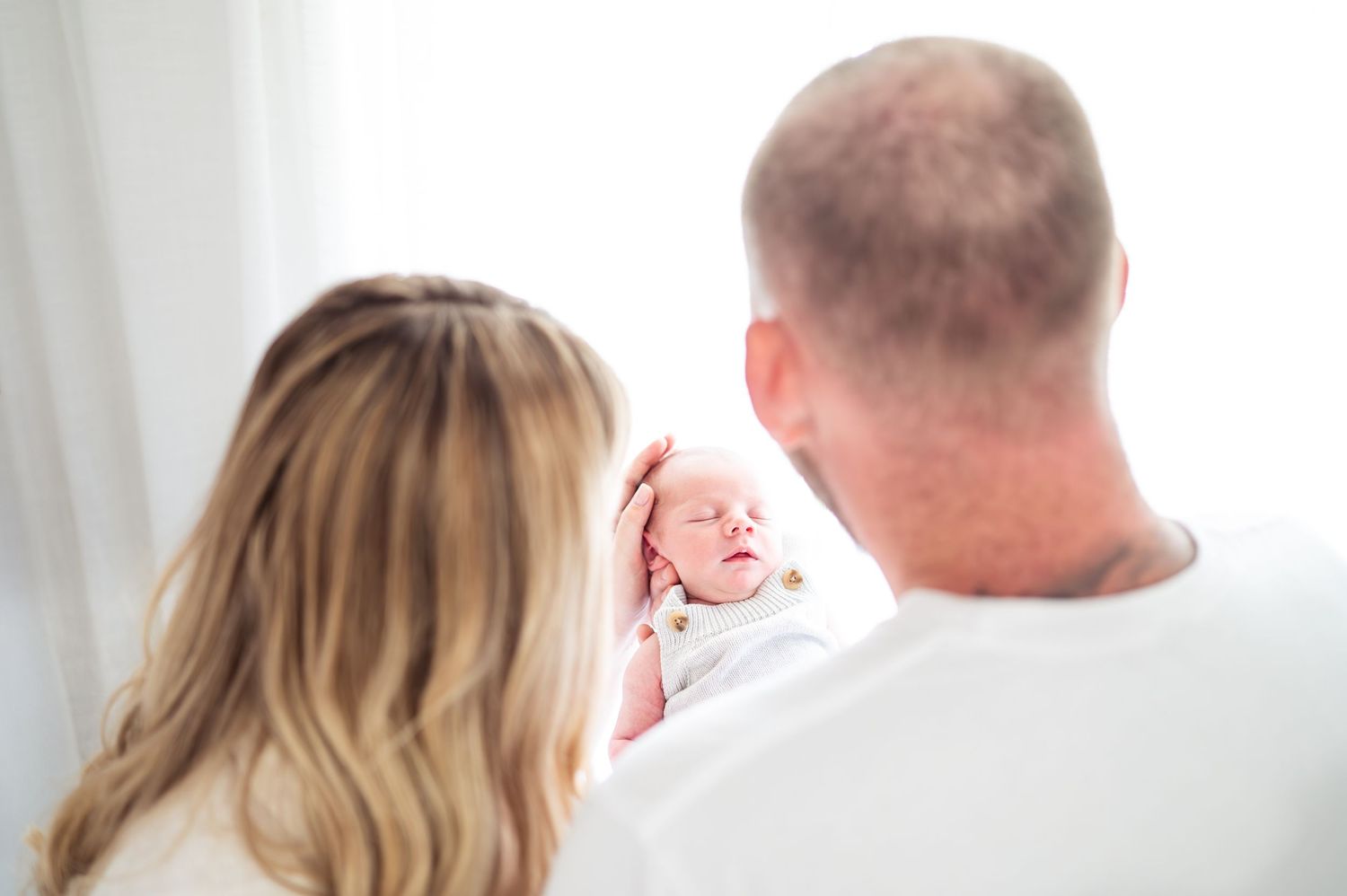 Minimalist white studio portraits capturing tender family moments.