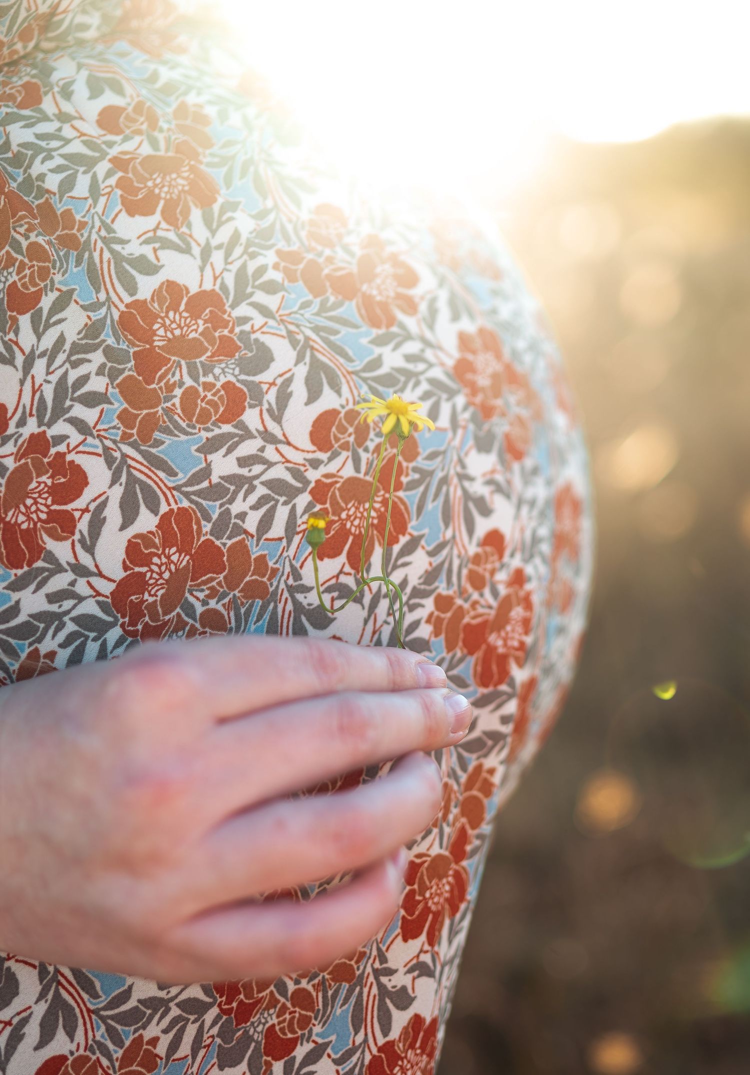 Close-up detail of hands against a floral patterned fabric in warm sunlight.