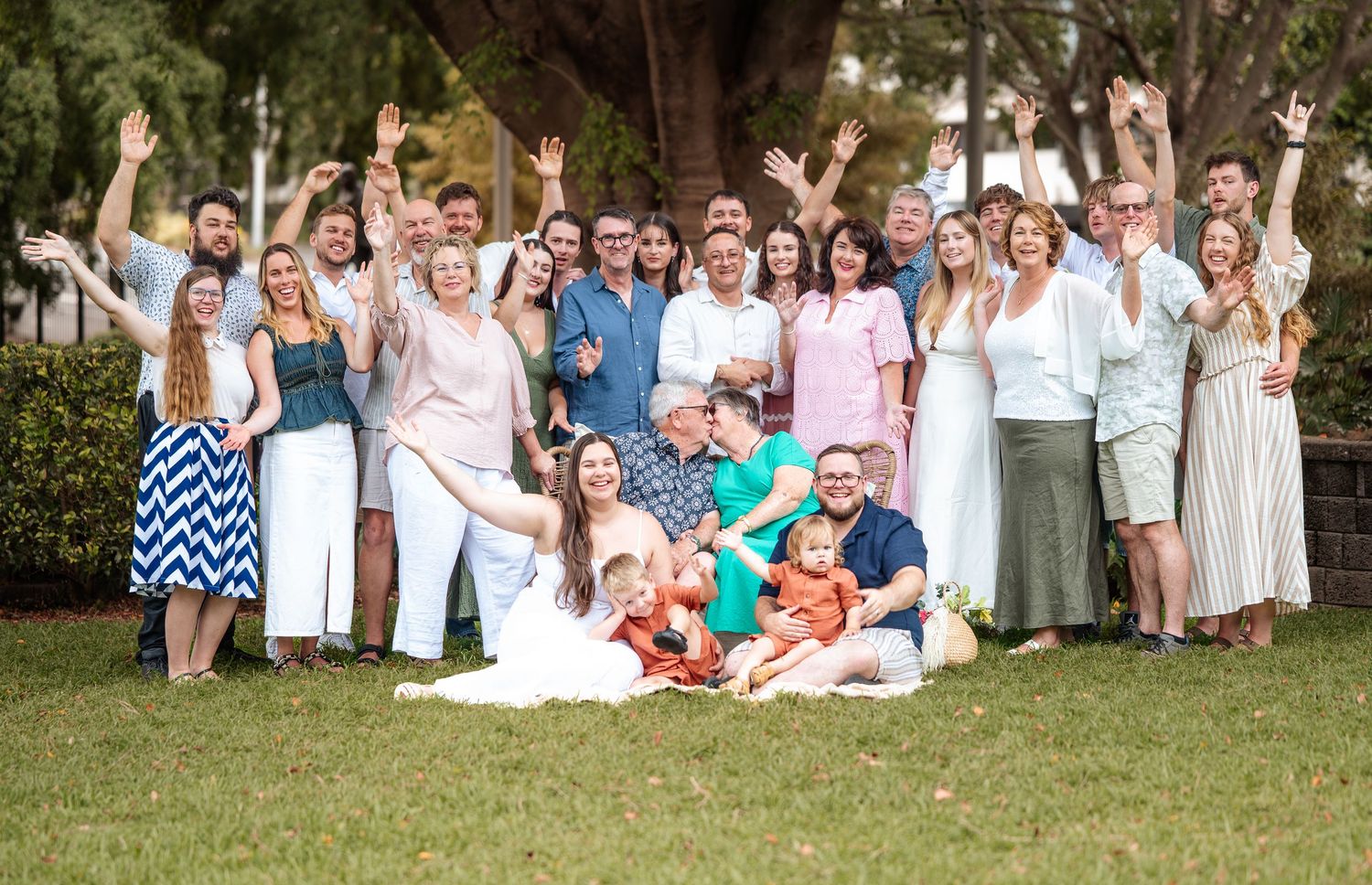 Large group photo of people dressed in coordinating white and blue outfits on grass.