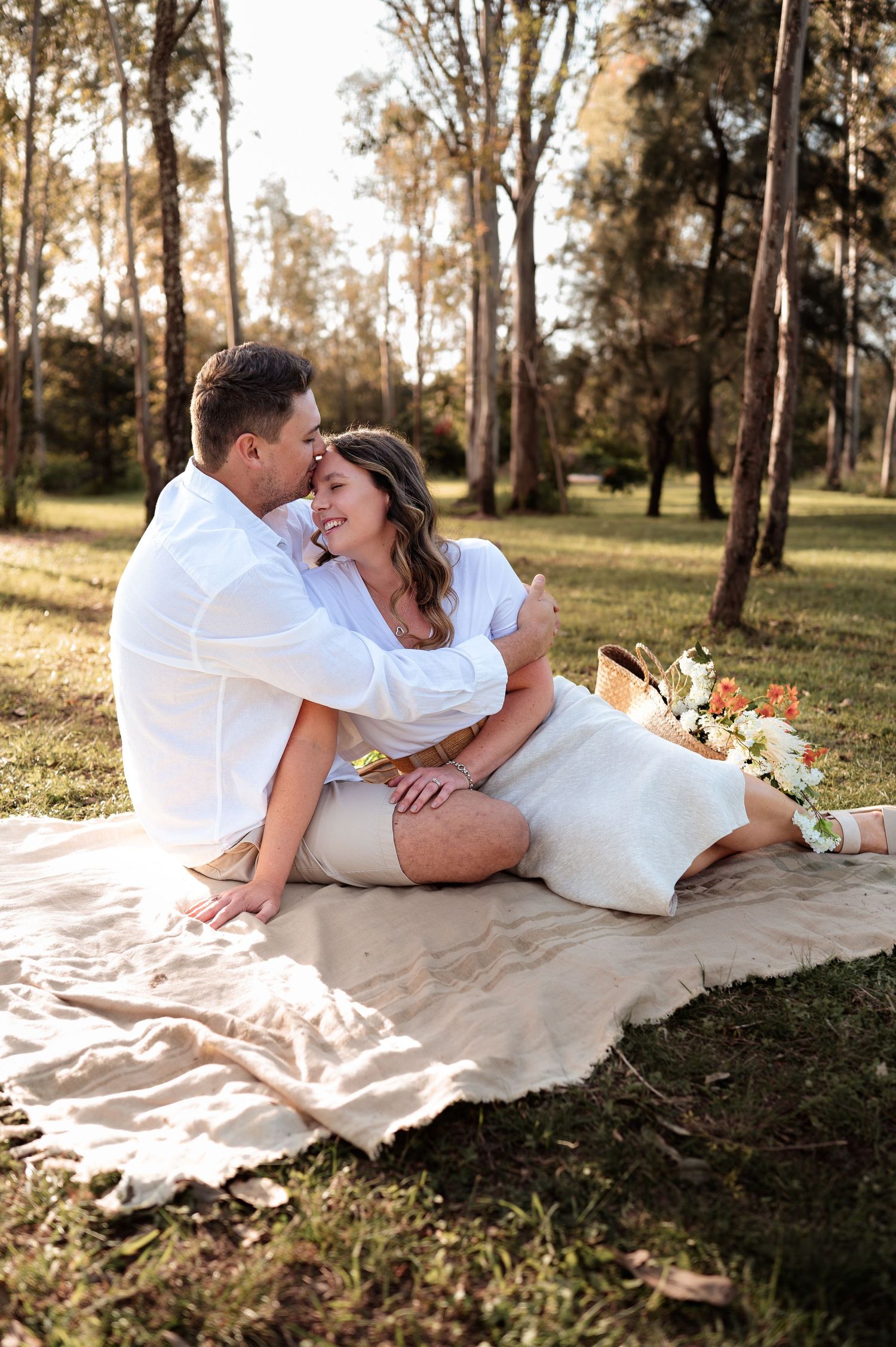 Romantic sequence on a blanket in a wooded area during golden hour.