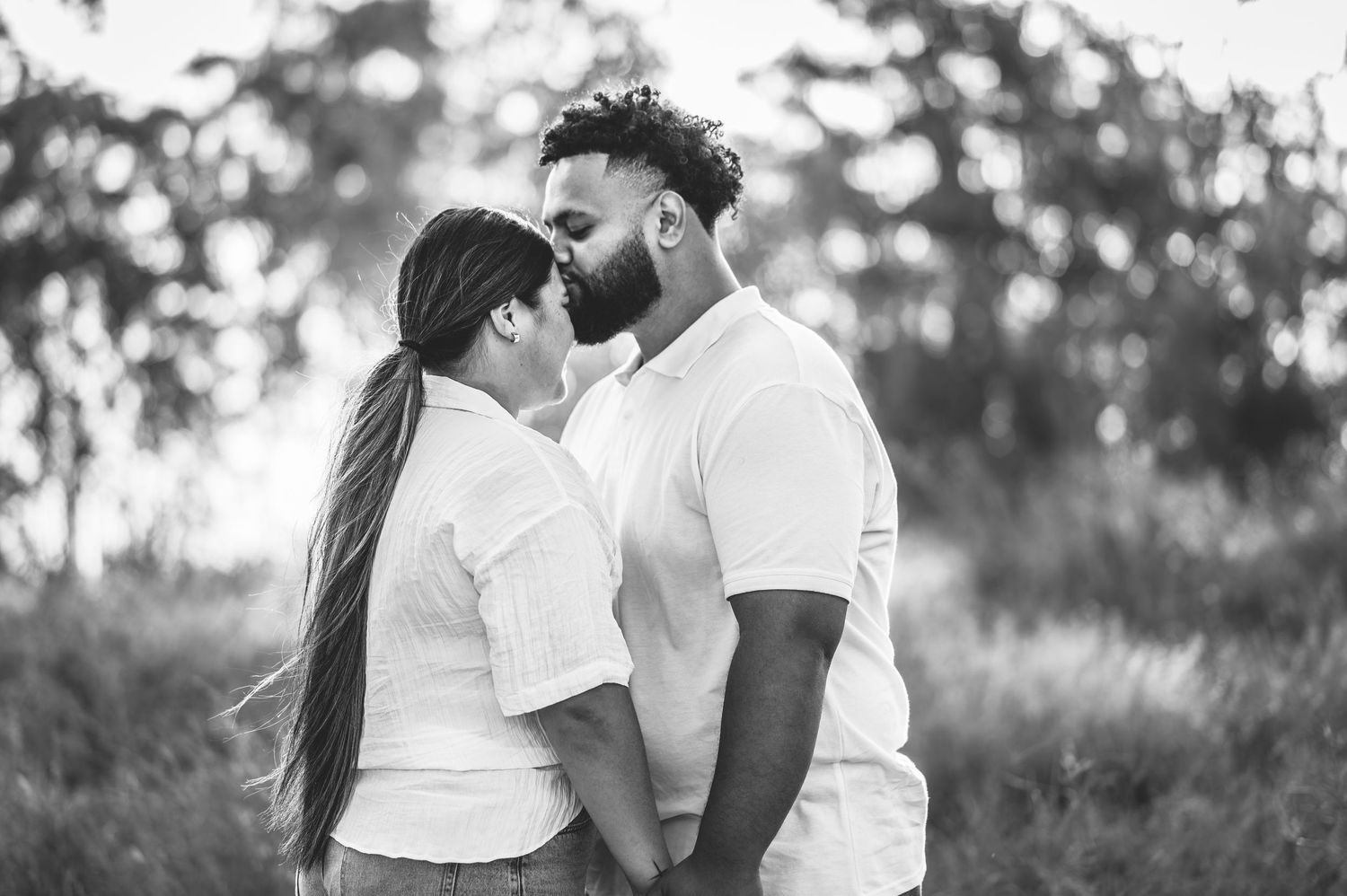 Romantic couple in white outfits sharing intimate moments in a black and white photo series.