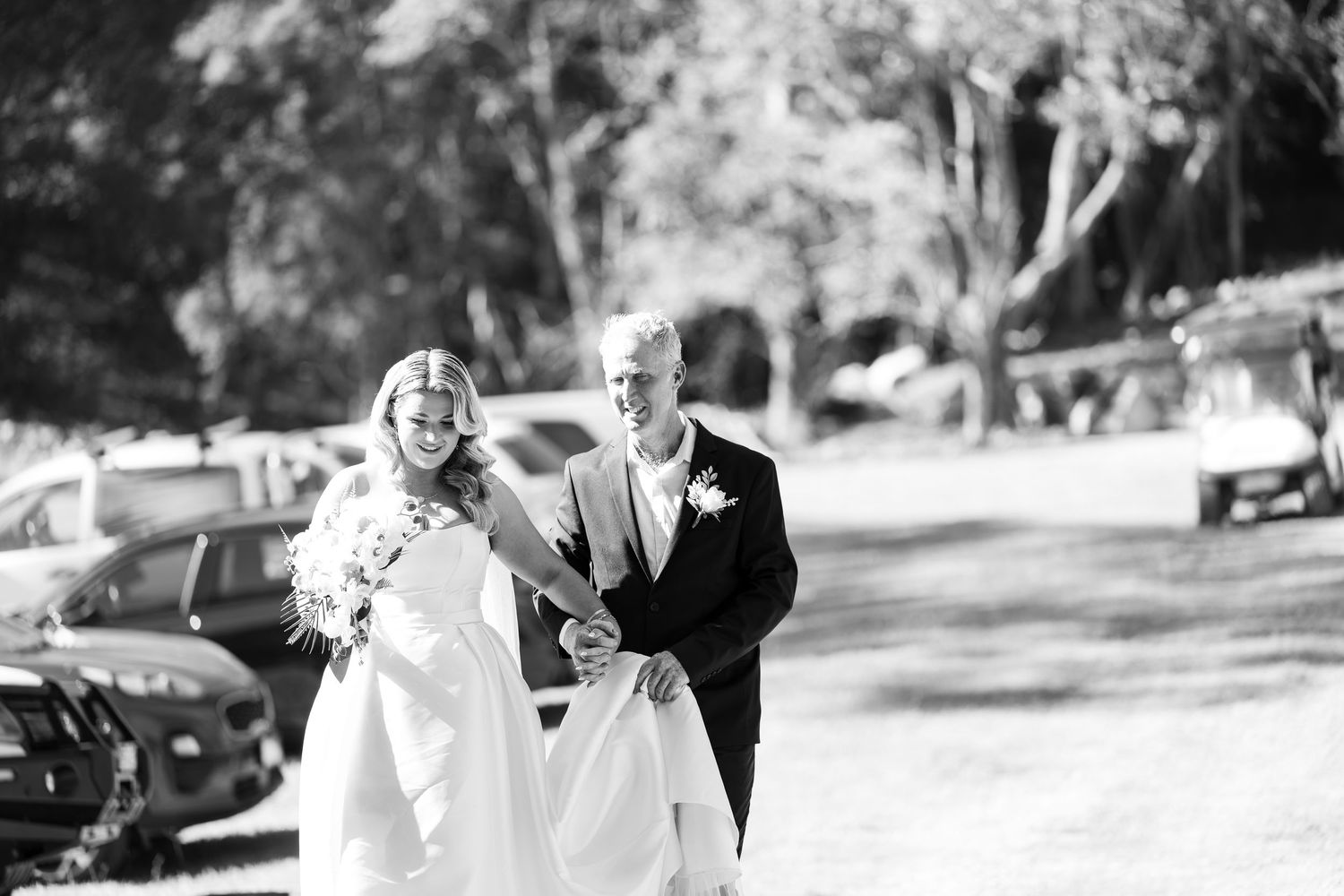 Bride and groom walking together outdoors in black and white wedding photo.
