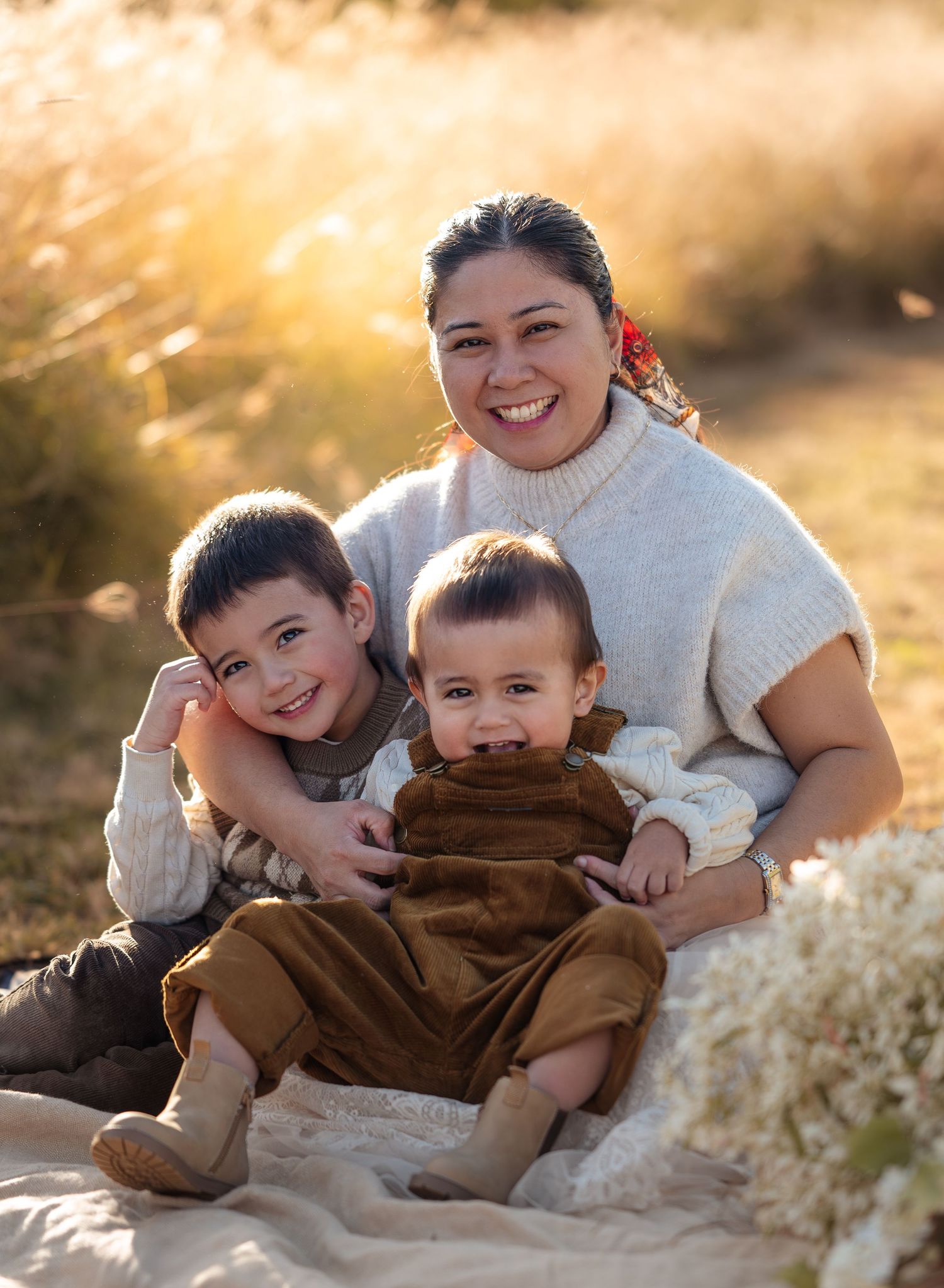 Family members cuddling together on a blanket during an outdoor sunset photo session.