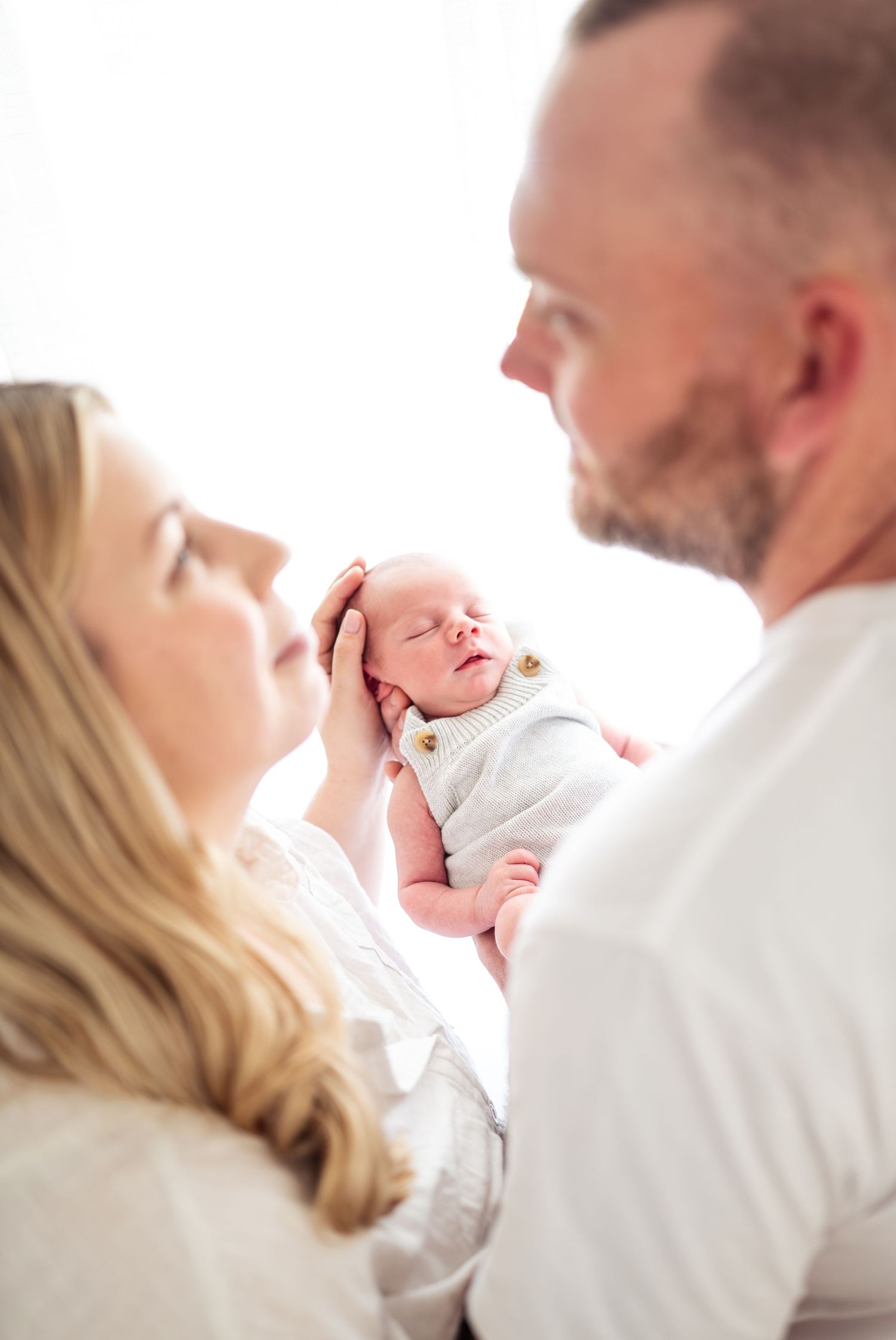 Tender family moment captured against white background in soft lighting.