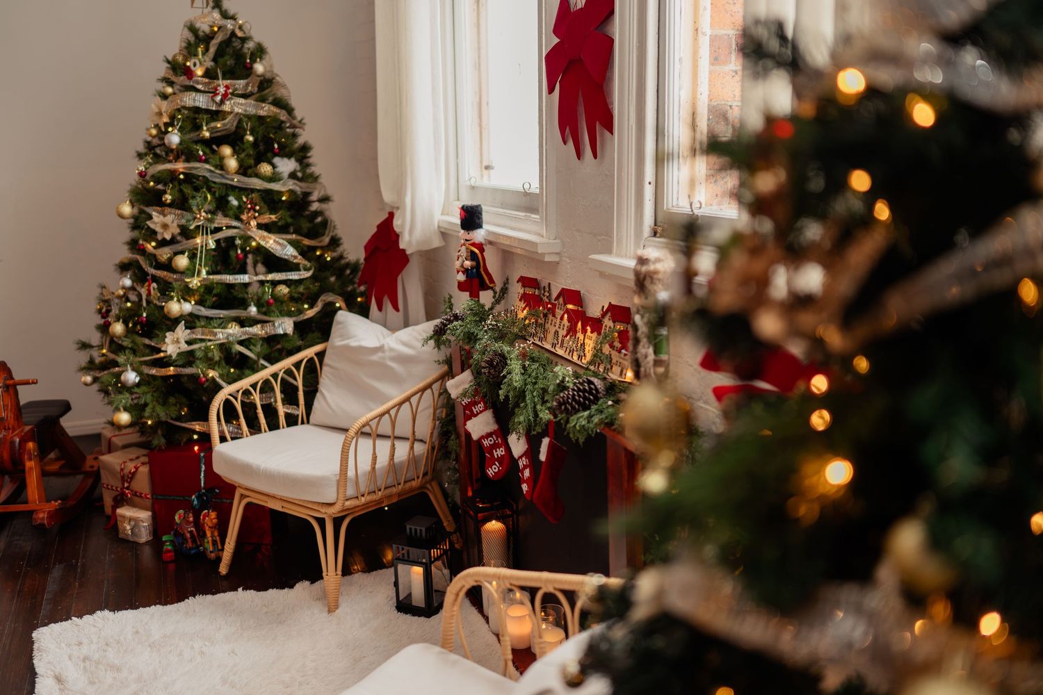 Cozy Christmas living room with decorated tree, wrapped gifts, rattan chair, and festive stockings by the window.