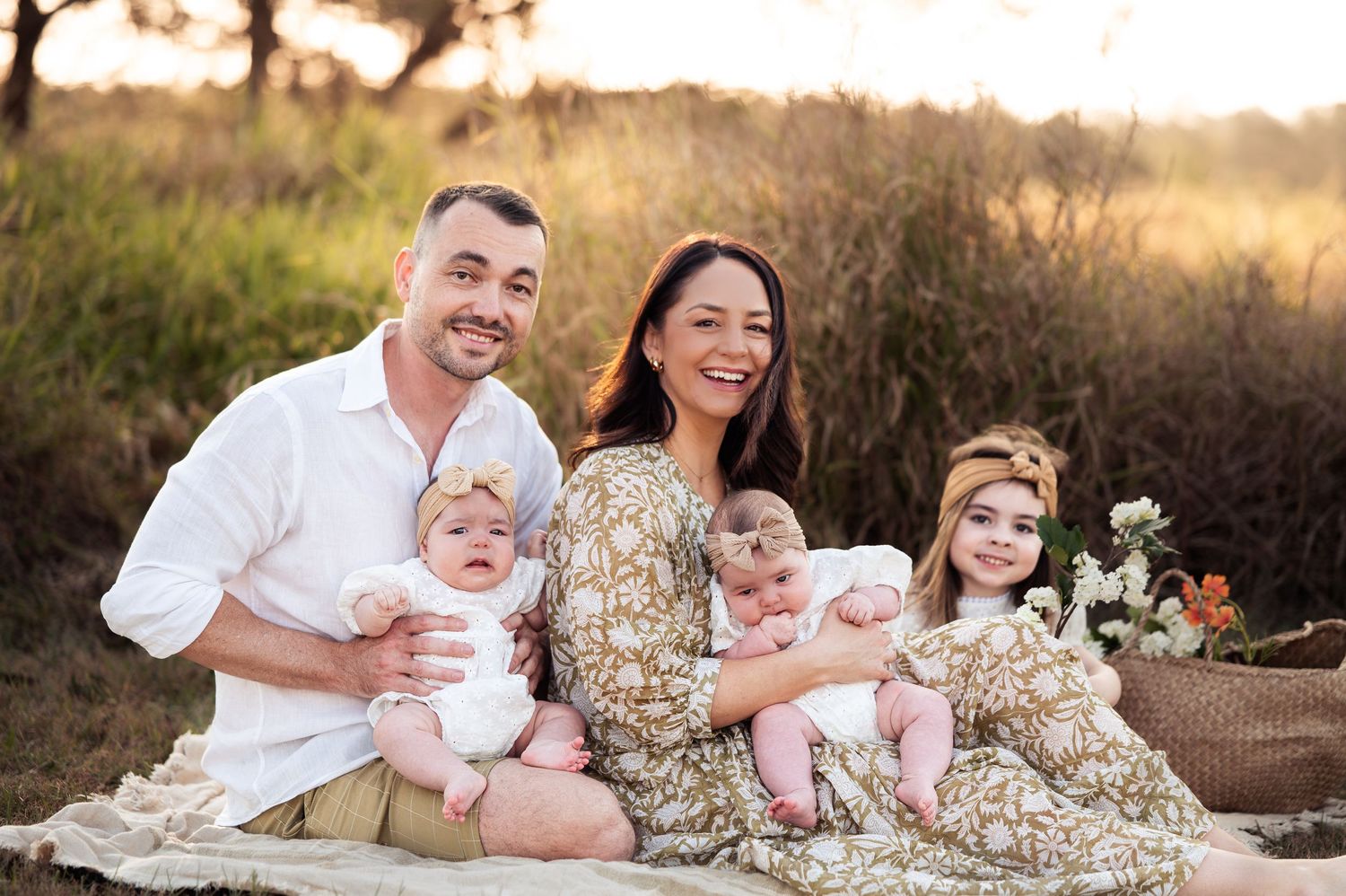 Family portrait series at sunset in a field with white wildflowers.