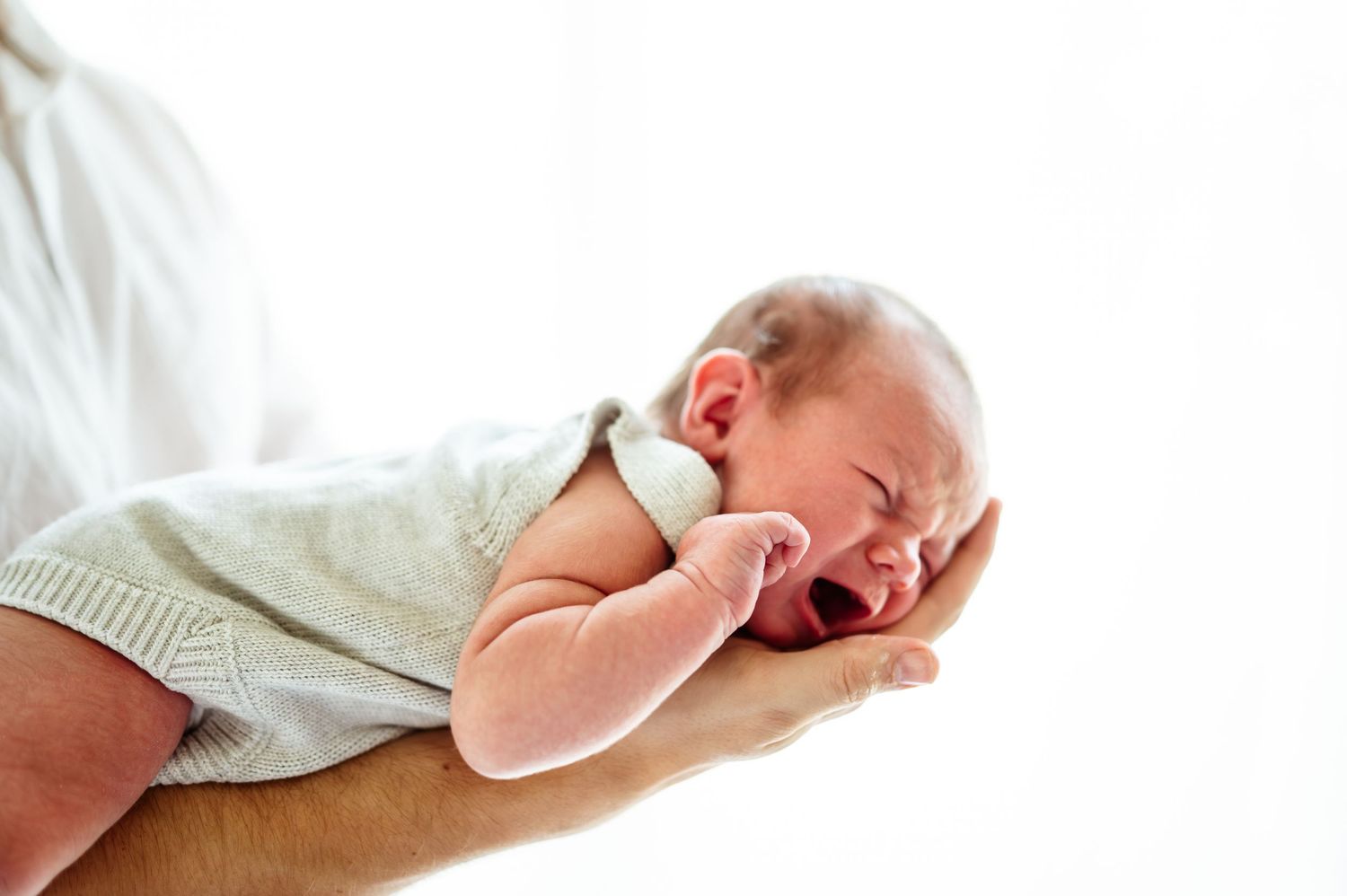 Sleeping newborn wrapped in white fabric with gentle lighting.