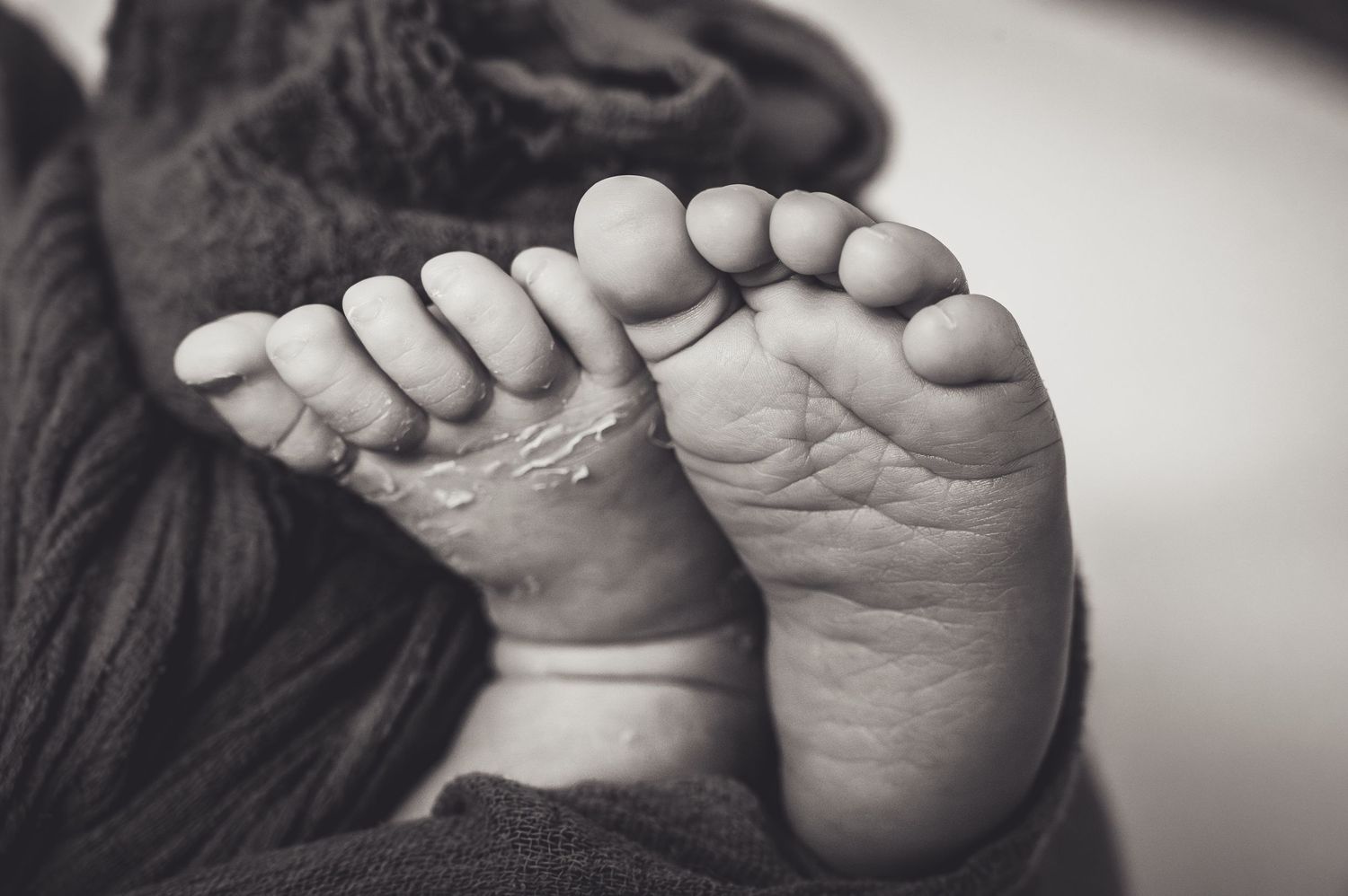 Black and white close-up of tiny newborn baby toes.