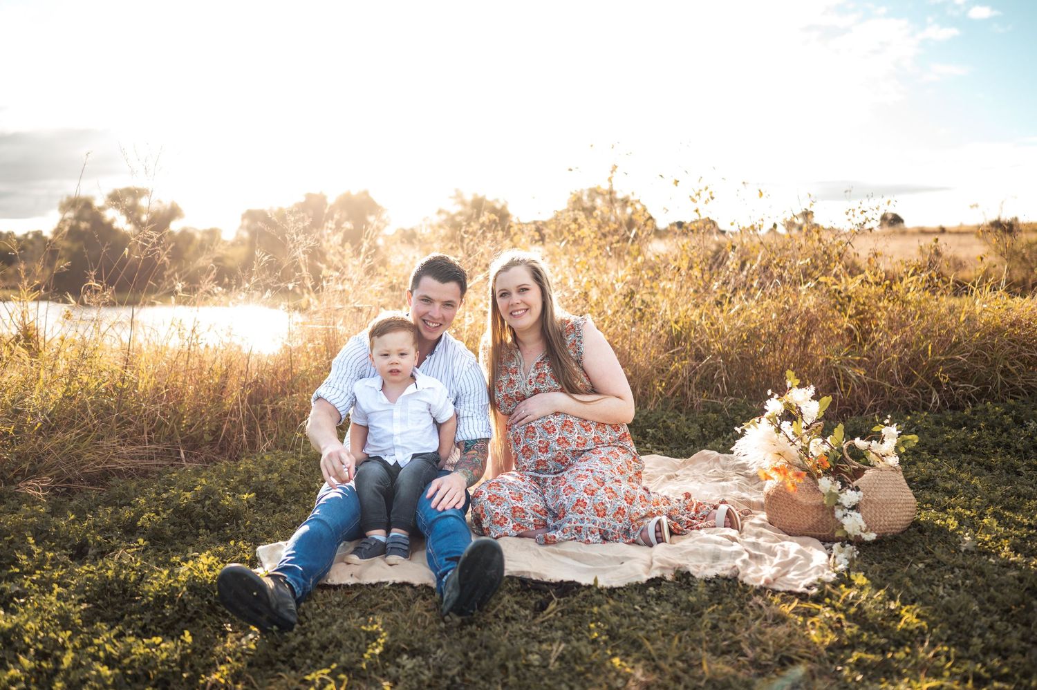 Family relaxes on blanket during sunset photoshoot in wildflower field.