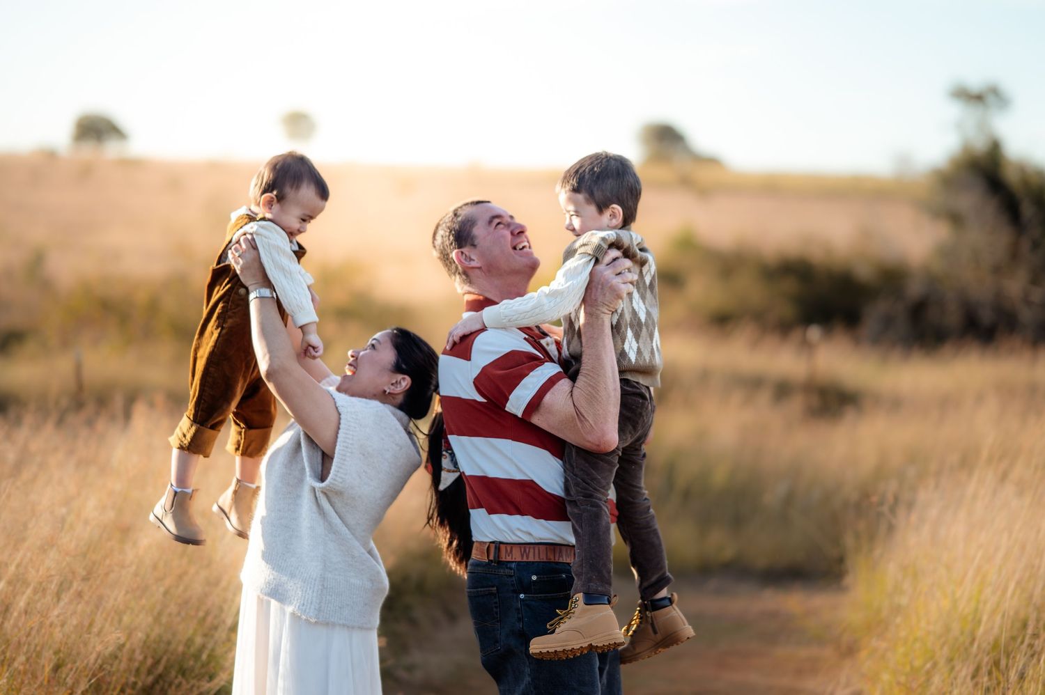 Playful family moments captured in a sun-drenched field during golden hour.