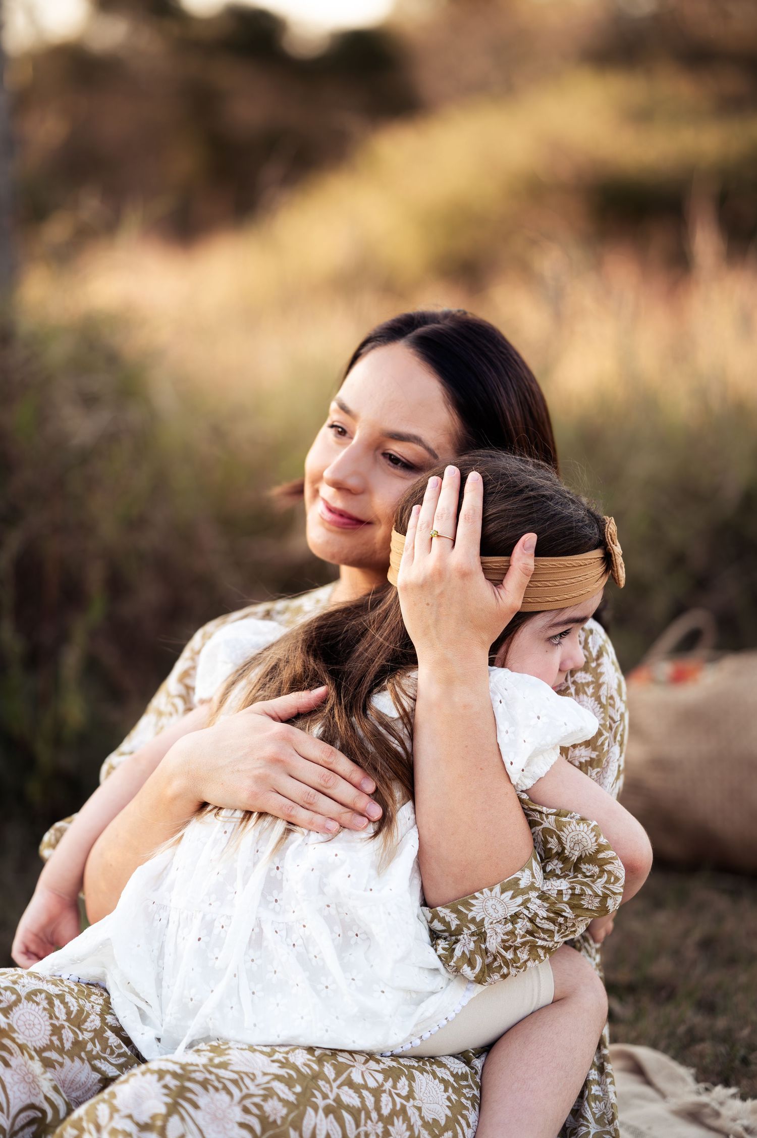 Two people share tender embraces in a natural outdoor setting during sunset.