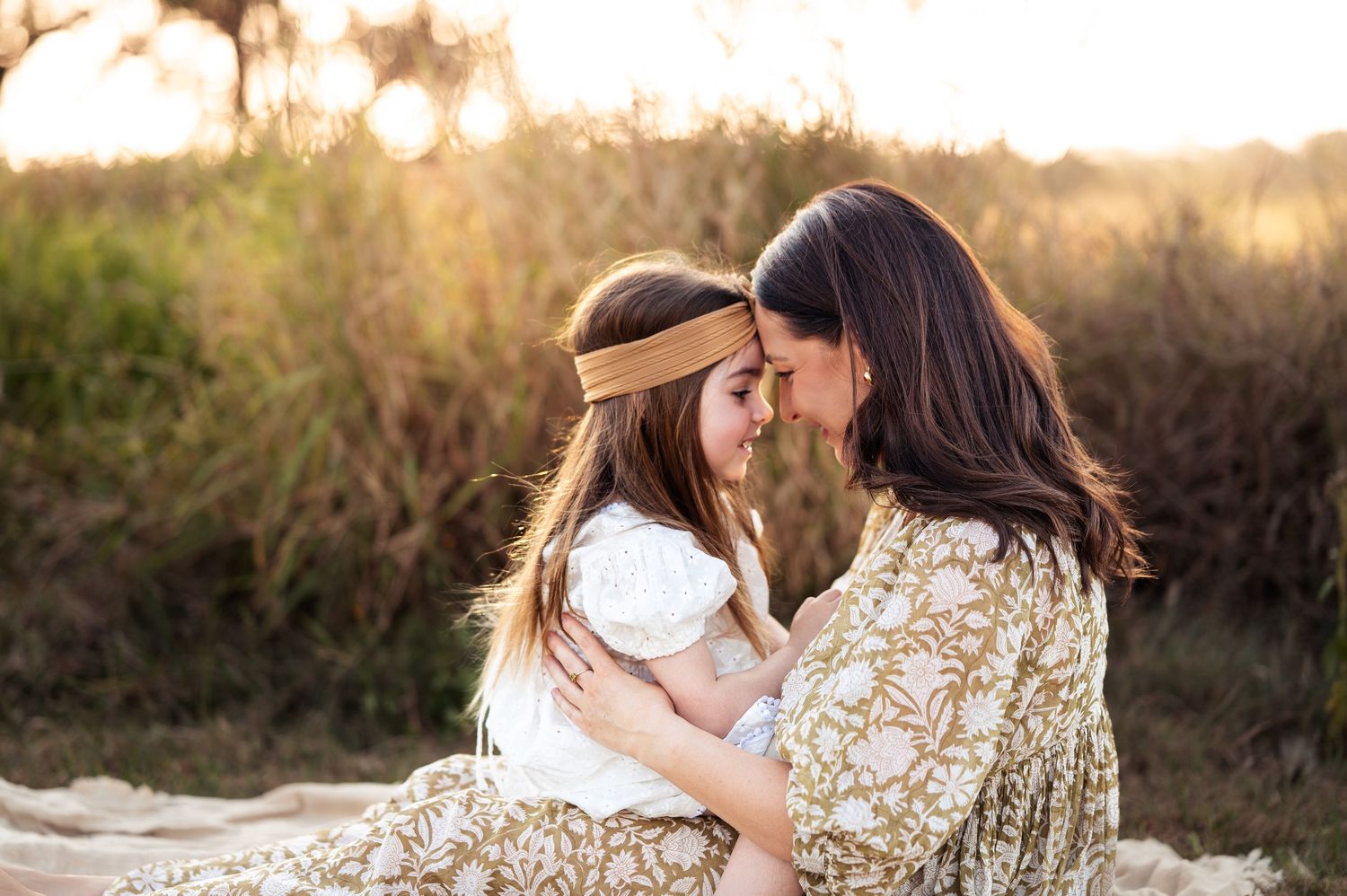 Tender family moments photographed in warm evening light against natural landscape.