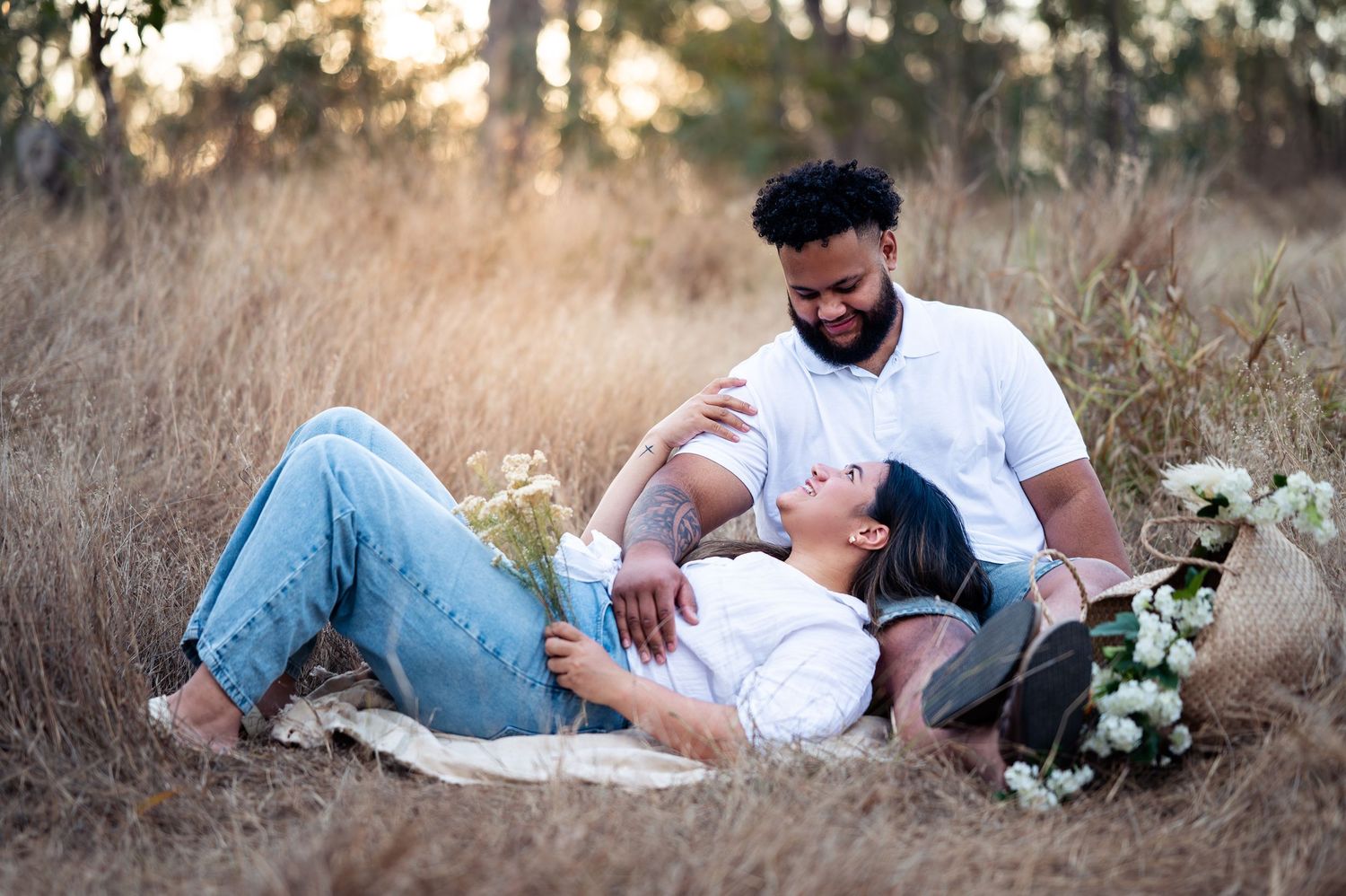Relaxed couple laying on ground during sunset photo session in field.