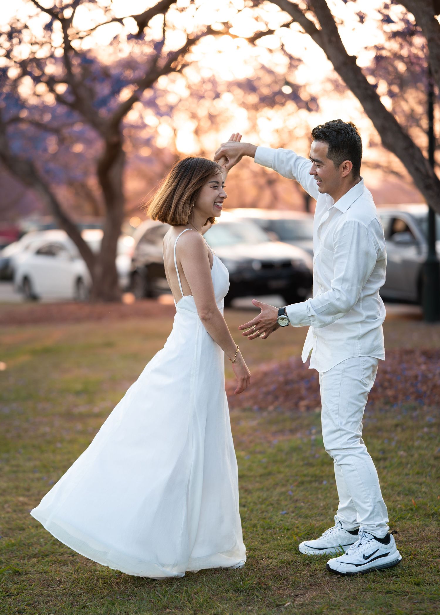 A playful dancing sequence in white outfits against a sunset backdrop with cherry blossom trees.