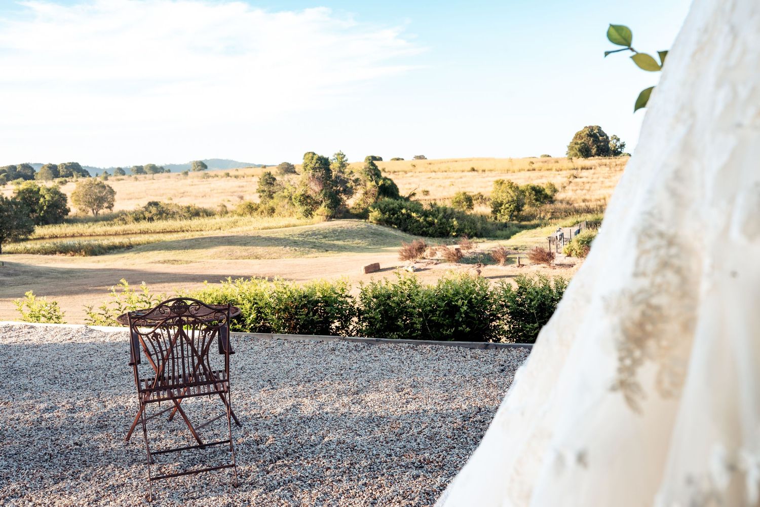 White wedding dress details against a desert landscape with rustic bench in background.