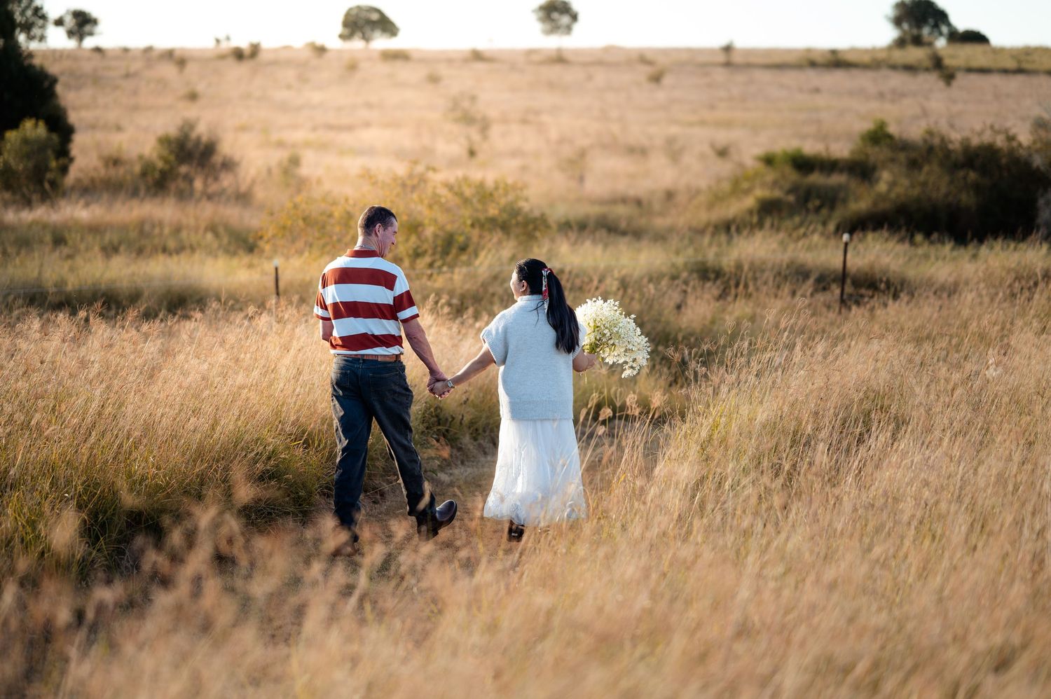 Family walking through a golden grass field during sunset photo session.