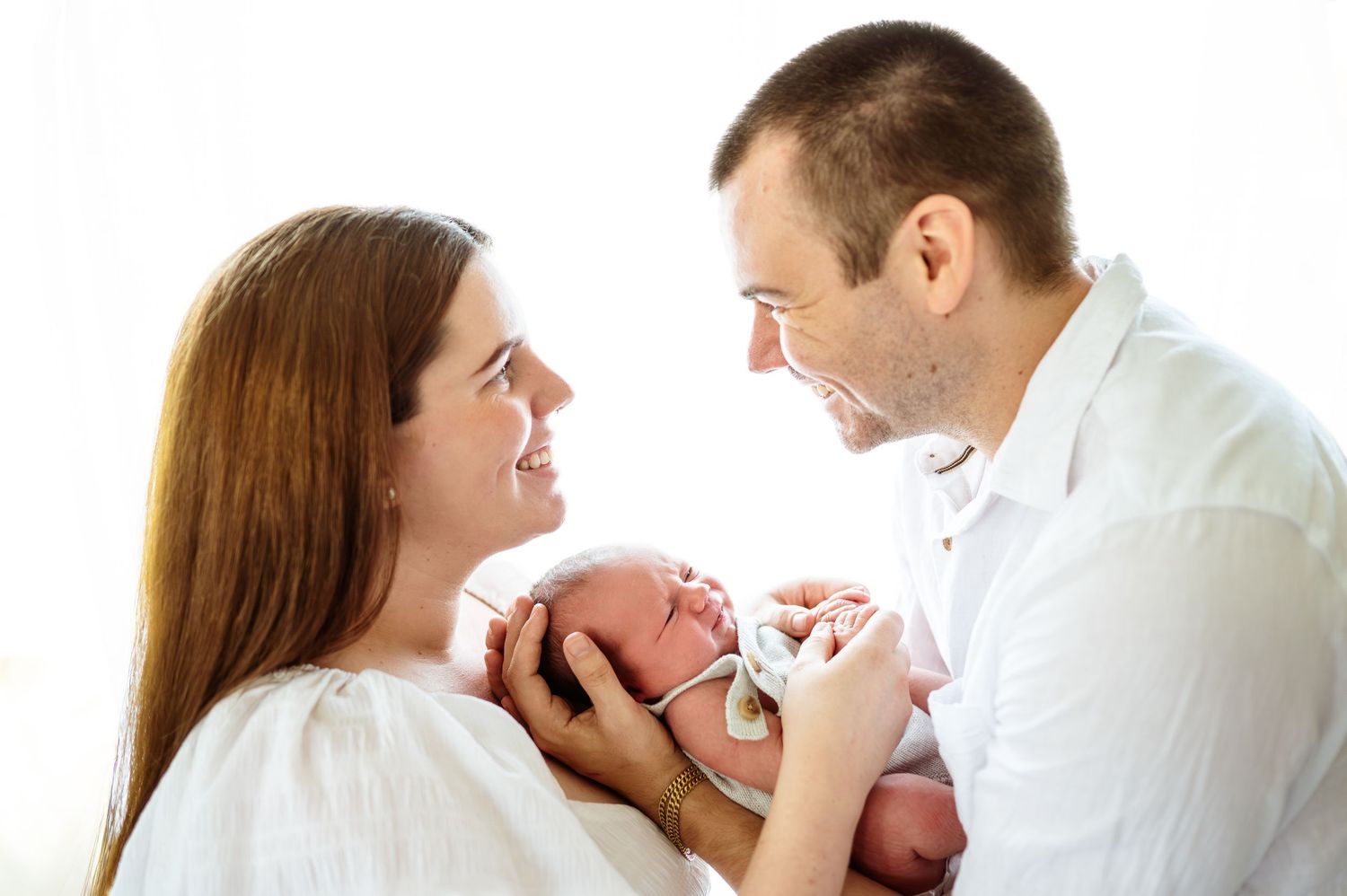 Family portrait series showing tender moments with newborn in white studio setting.