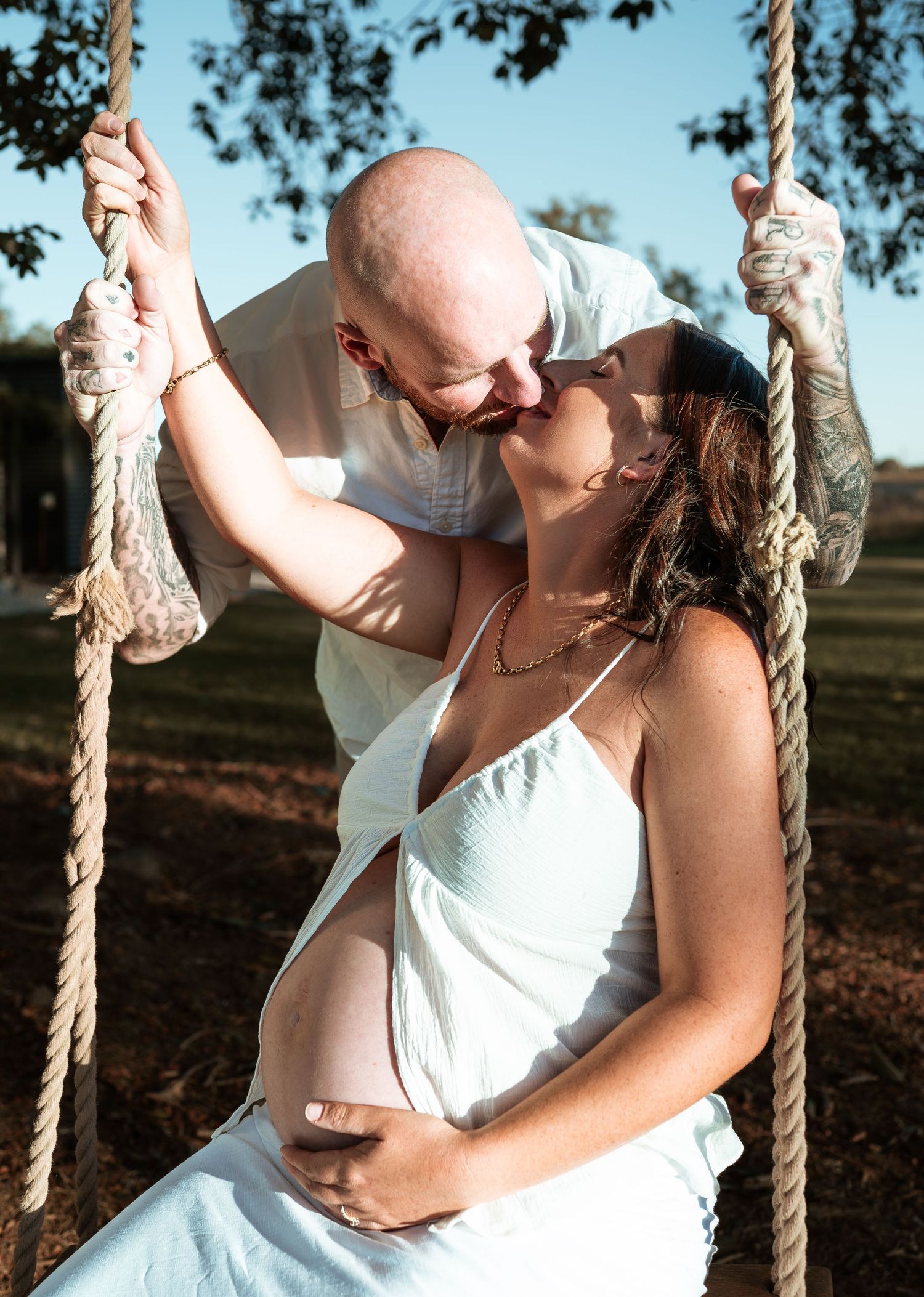 Romantic couple moment captured on rope swing during outdoor photoshoot.