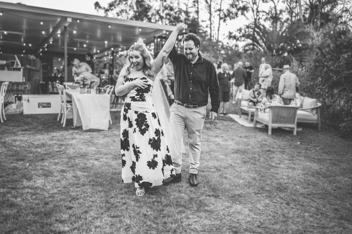 A couple dances together at an outdoor celebration in black and white.