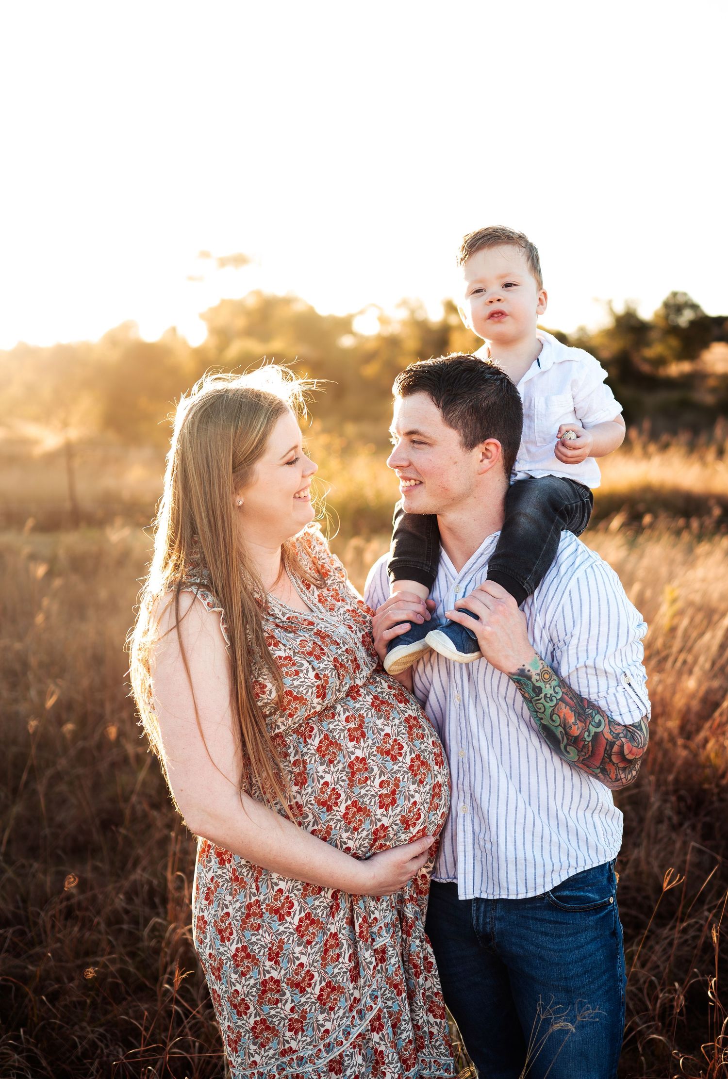 Family photo session in golden field during sunset with backlit glow.