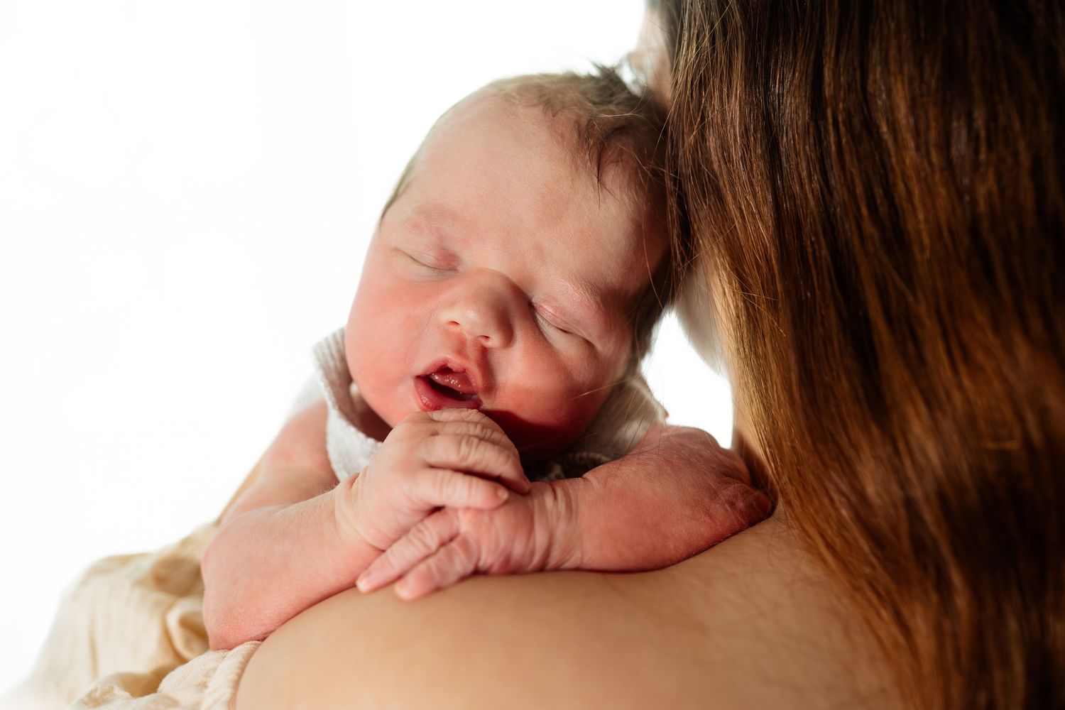Intimate close-up series of parent cradling newborn in natural light.