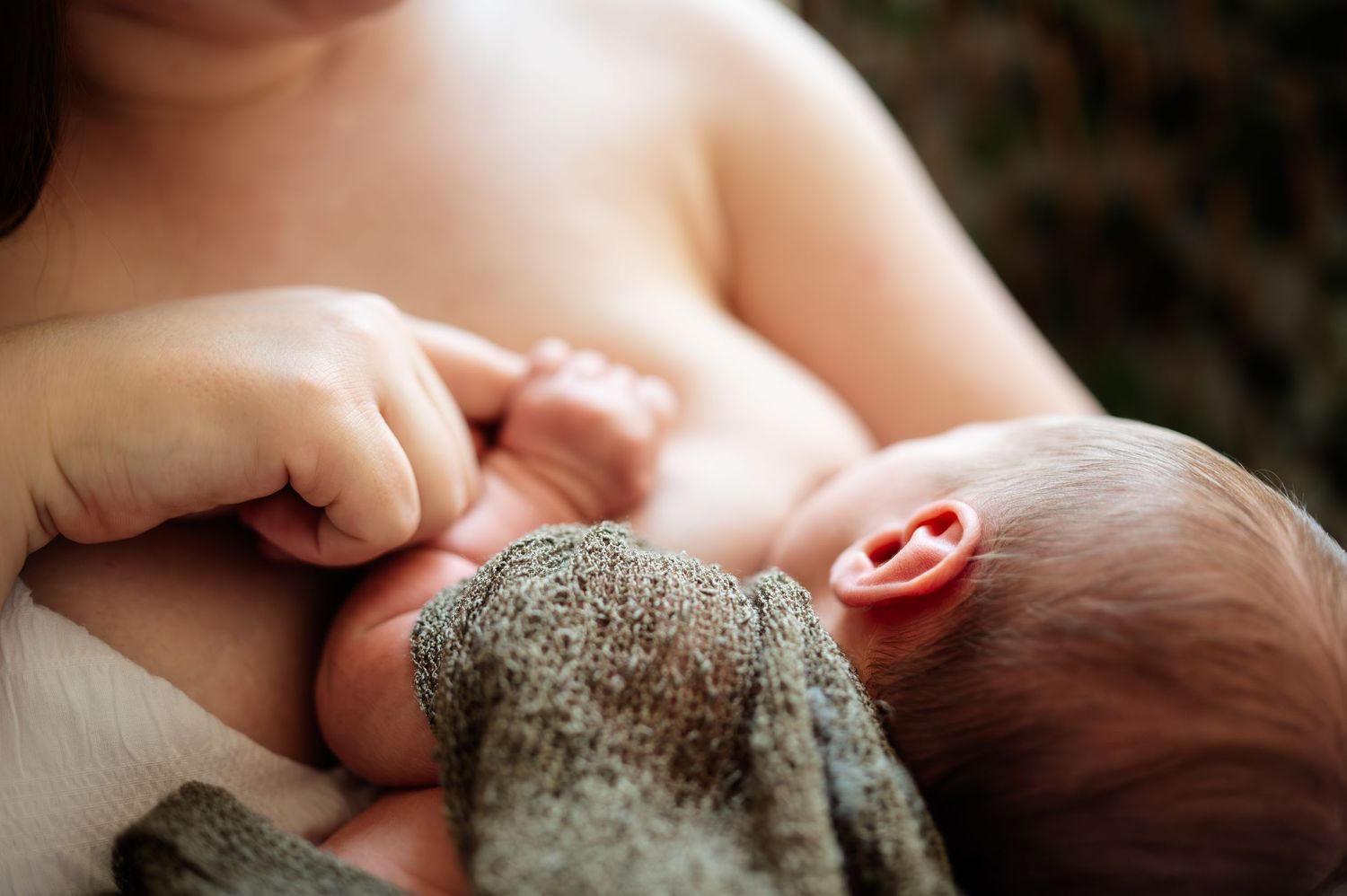 Artistic close-up of sleeping newborn with soft textured blanket.