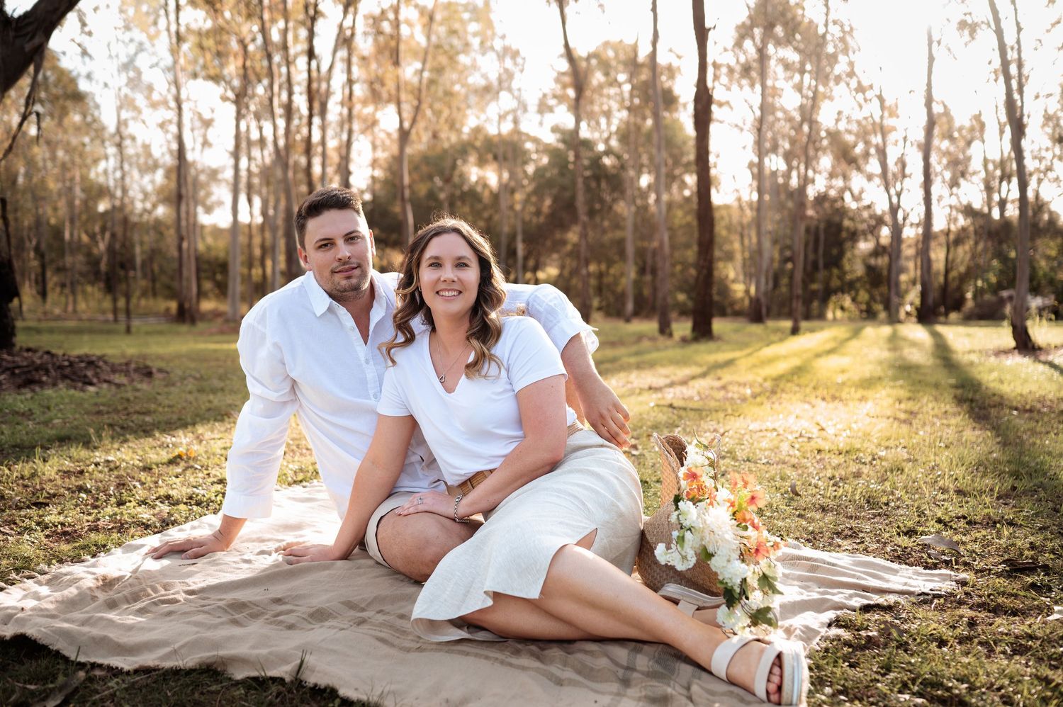 Loving sequence photographed on a blanket amid trees during sunset.