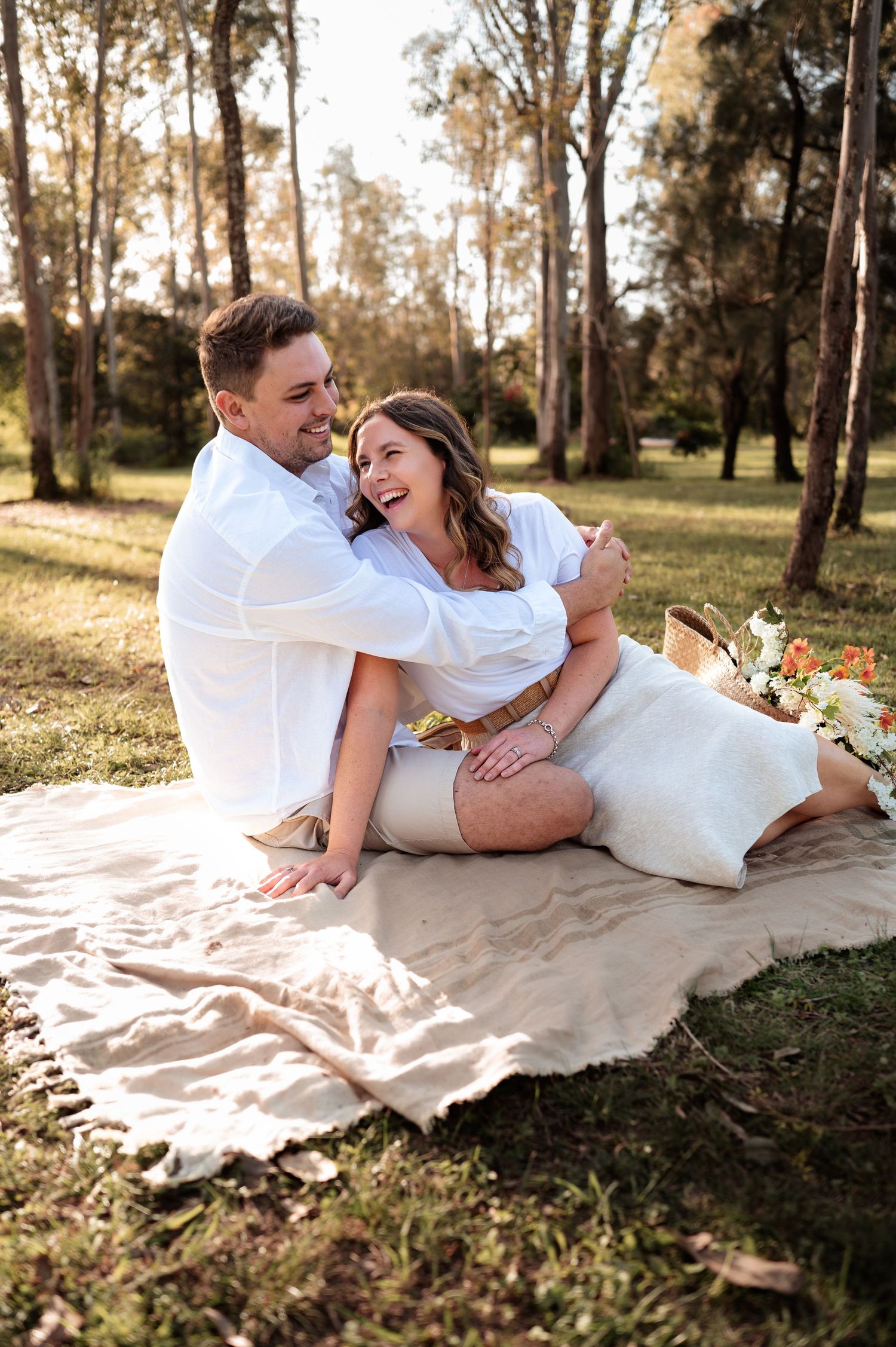 Couple relaxing together on picnic blanket during outdoor forest photoshoot.