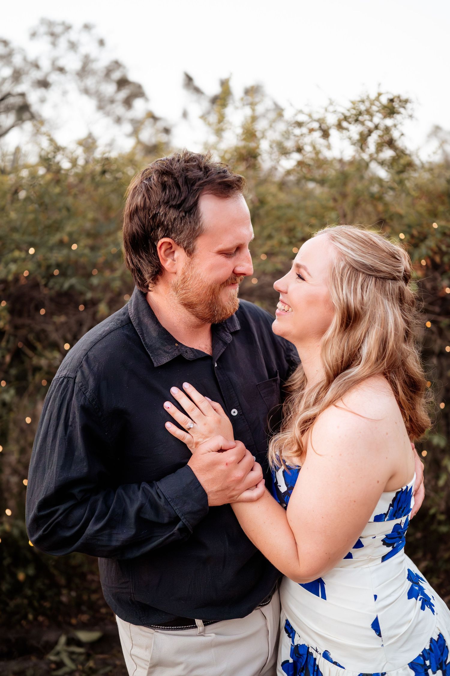 Romantic couple in blue and black attire sharing intimate moments outdoors.