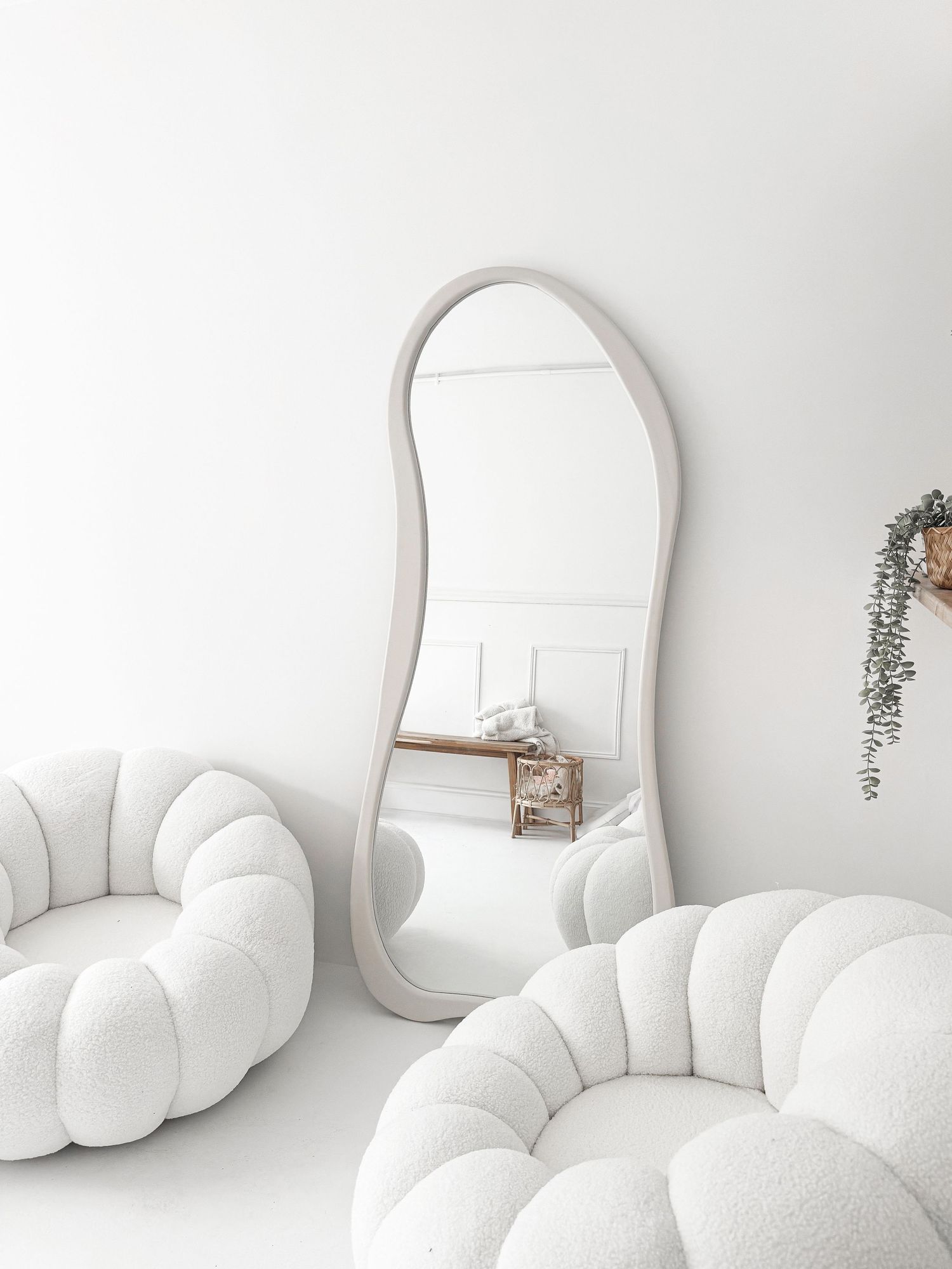 Elegant white studio with curved full-length mirror and two fluffy bubble sofas.