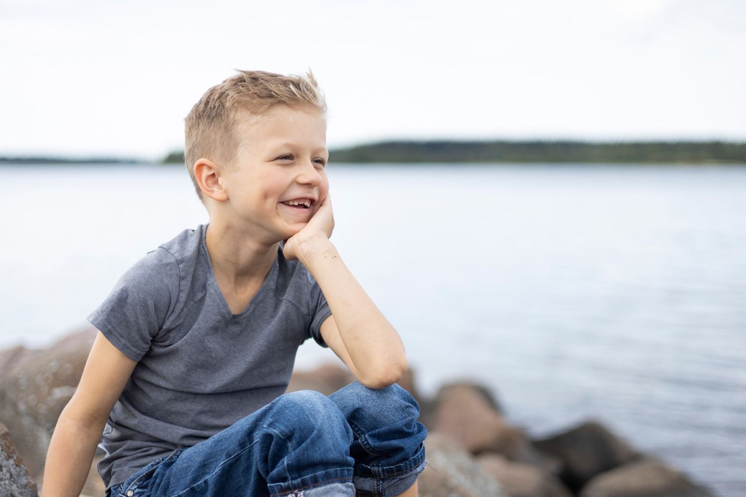 Poika nojaa omaan käteen ja hymyilee.