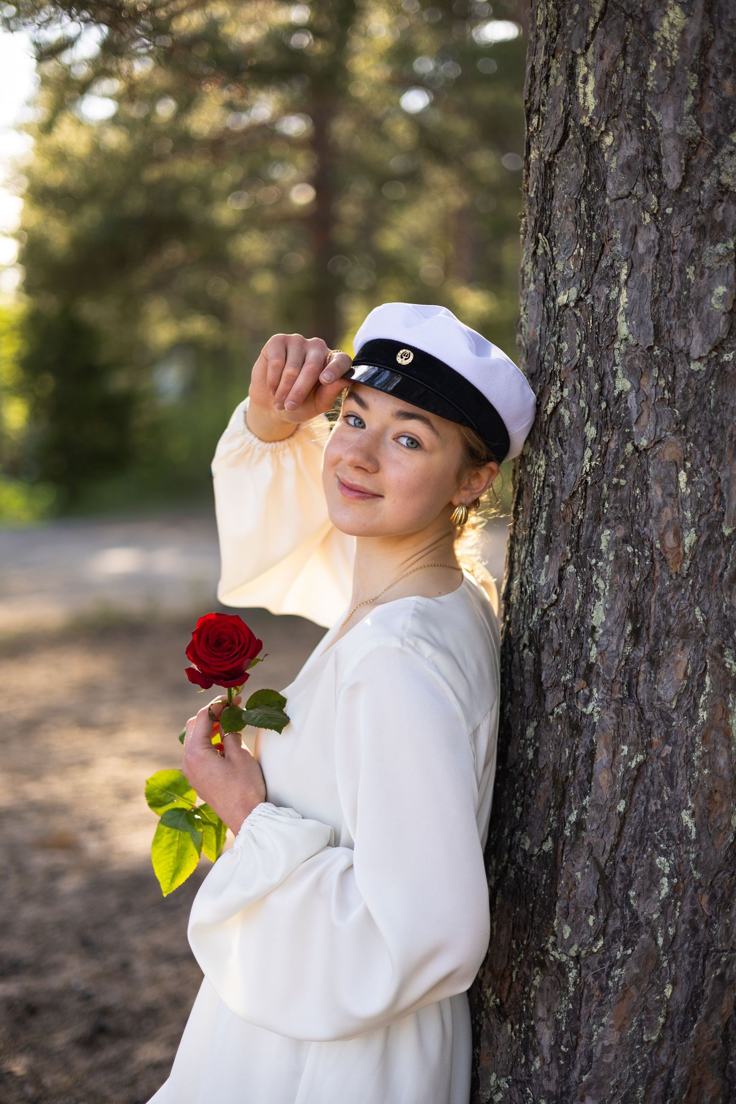 Tyttö nojaa puuhun valmistujaiskuvauksissa Haukiputaalla.