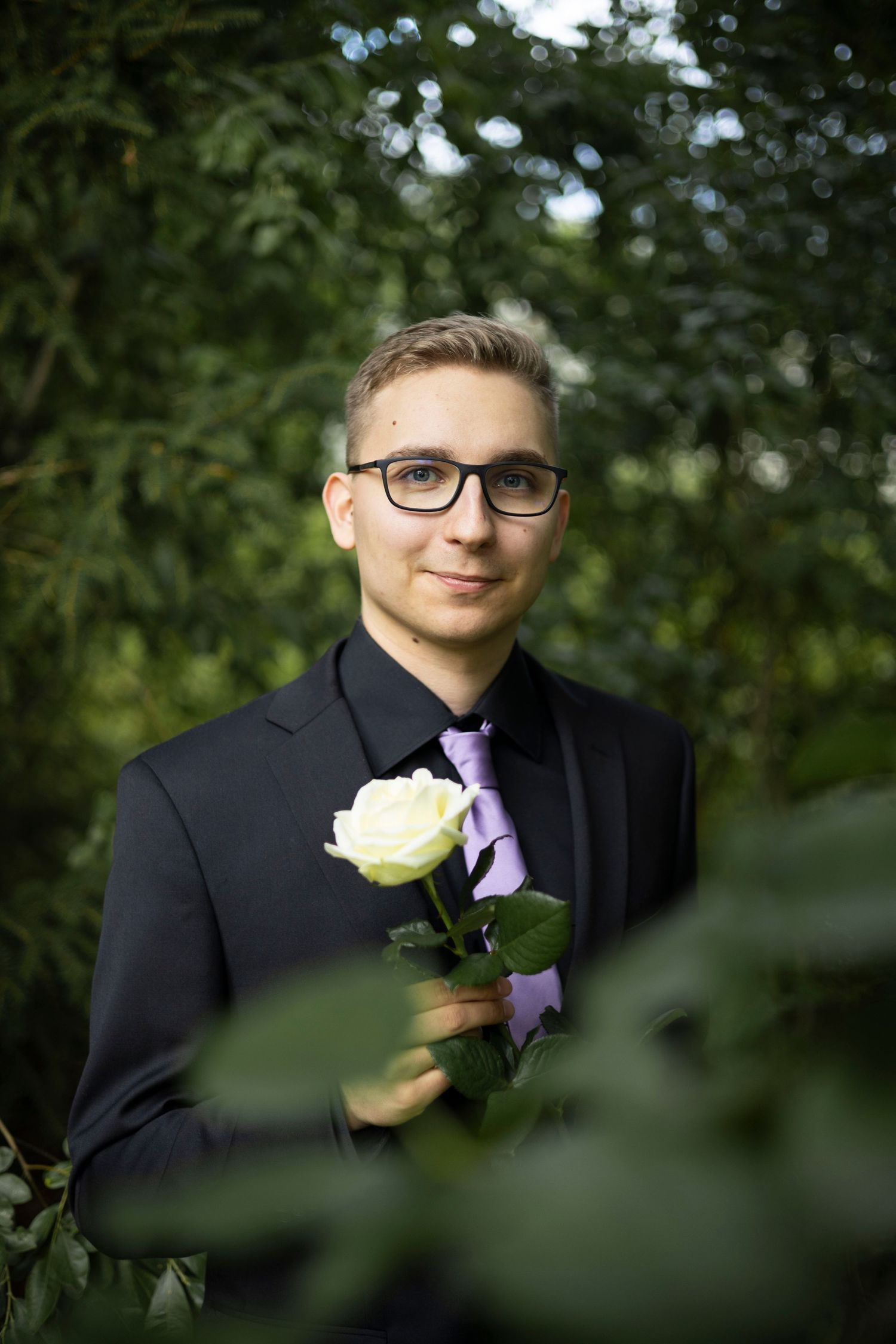 Mies poseeraa kukan kanssa ja hymyilee.