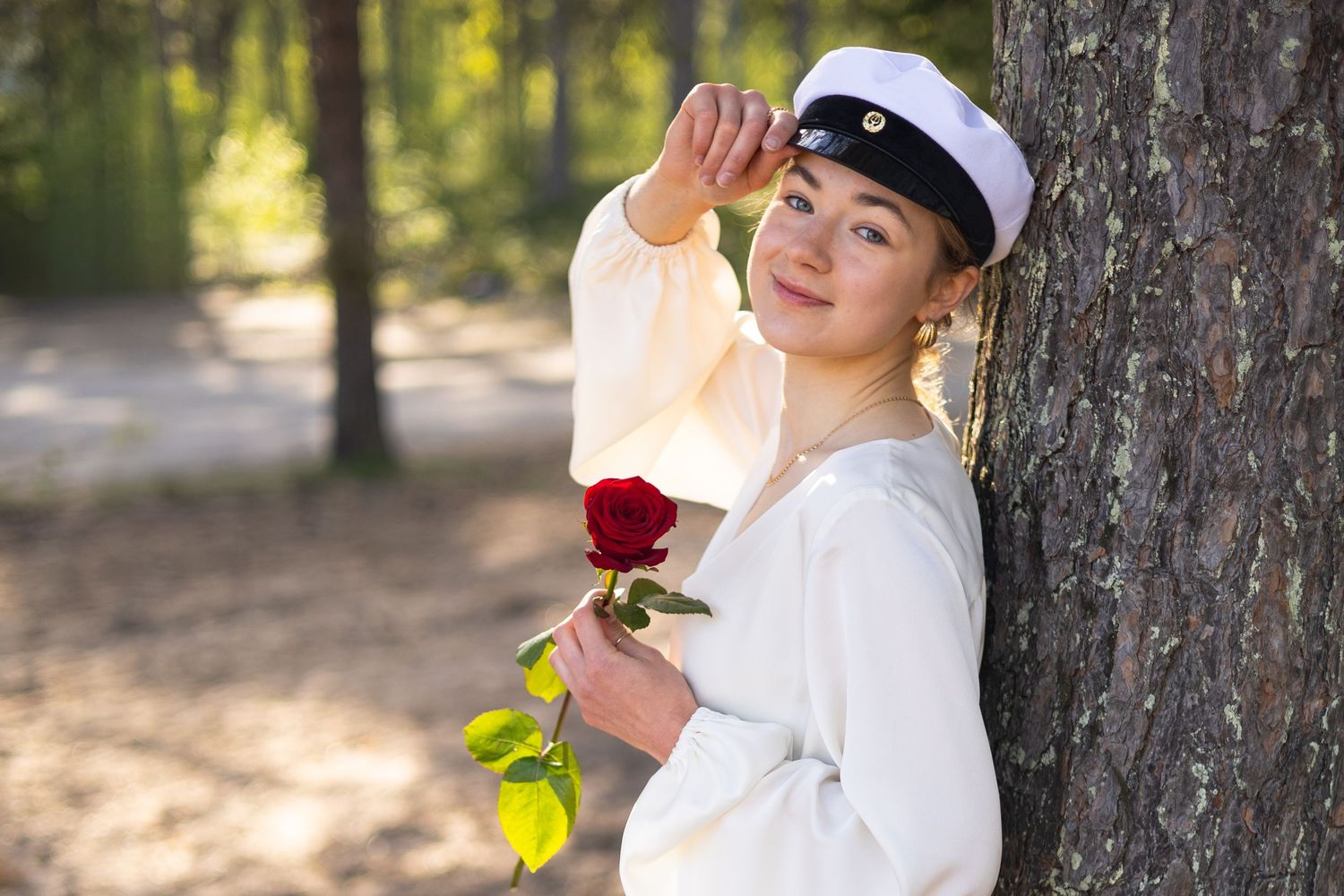 Tyttö nojaa puuhun valmistujaiskuvissa Haukiputaalla.
