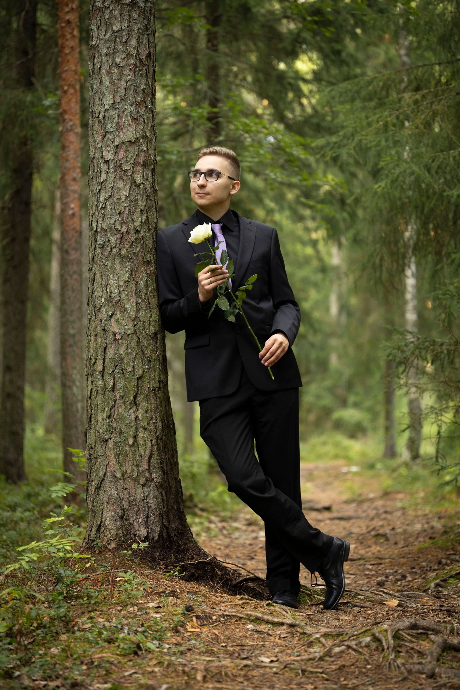 Mies nojaa puuhun ja pitää käsissään kukkaa Oulussa.