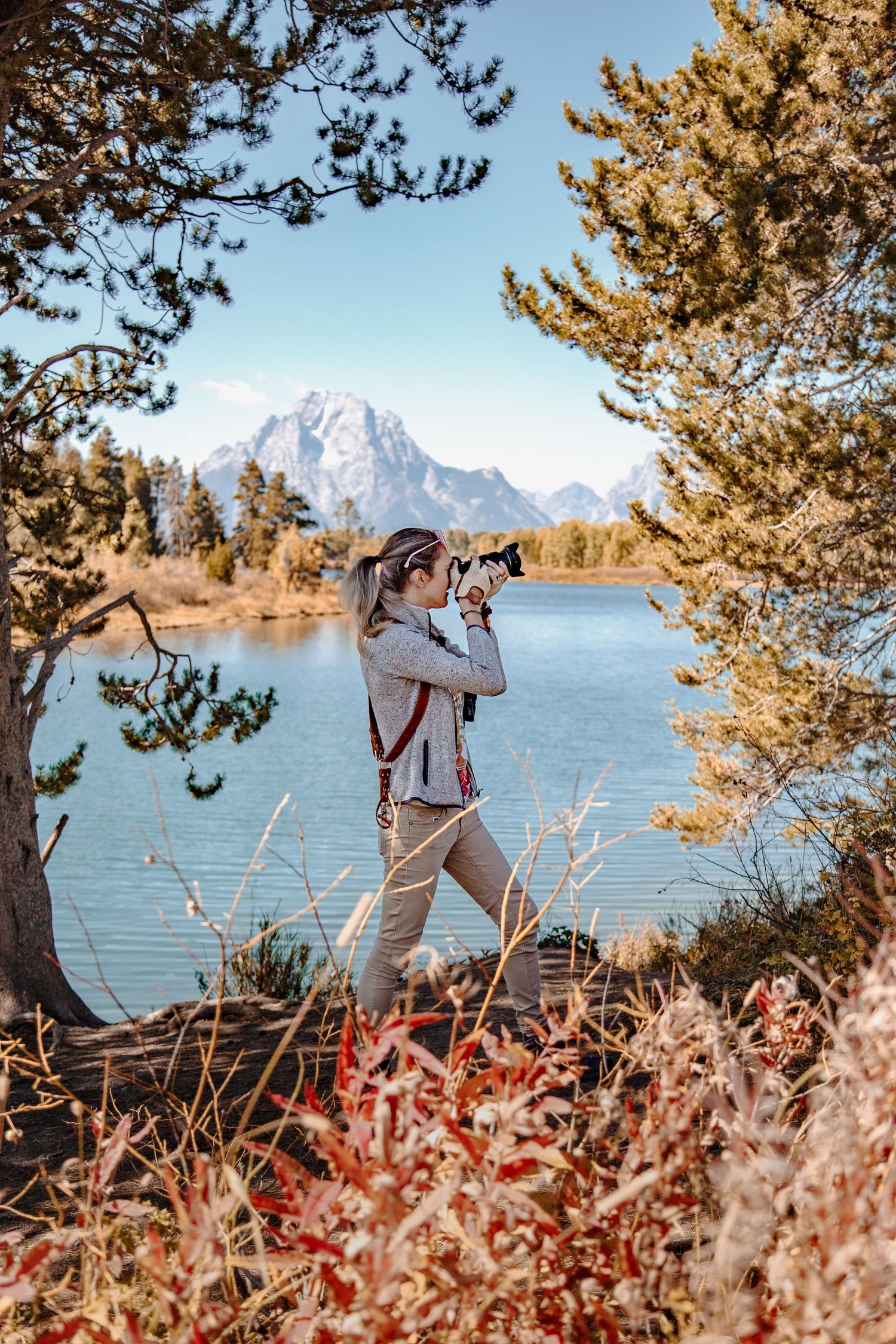 Photographer capturing scenic mountain landscape at Grand Teton National Park during autumn.