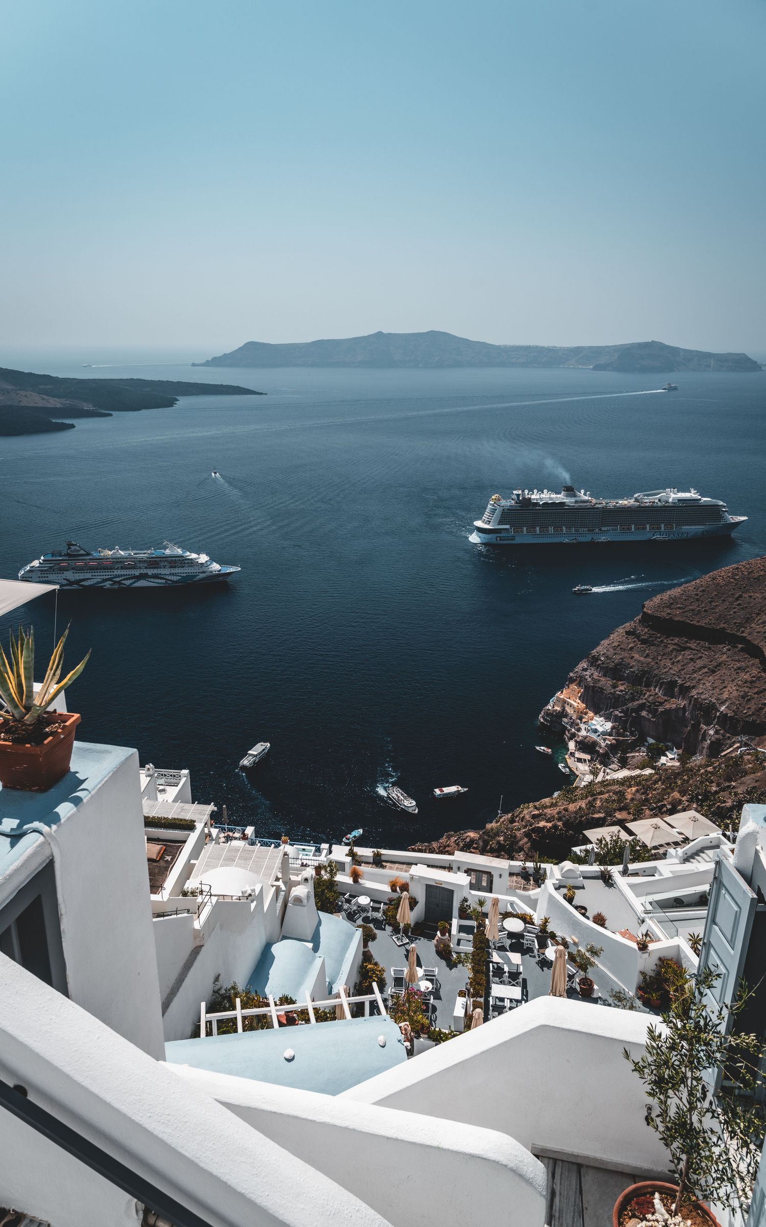 Panoramic view of Santorini caldera with cruise ships, white buildings cascading down volcanic cliffs.
