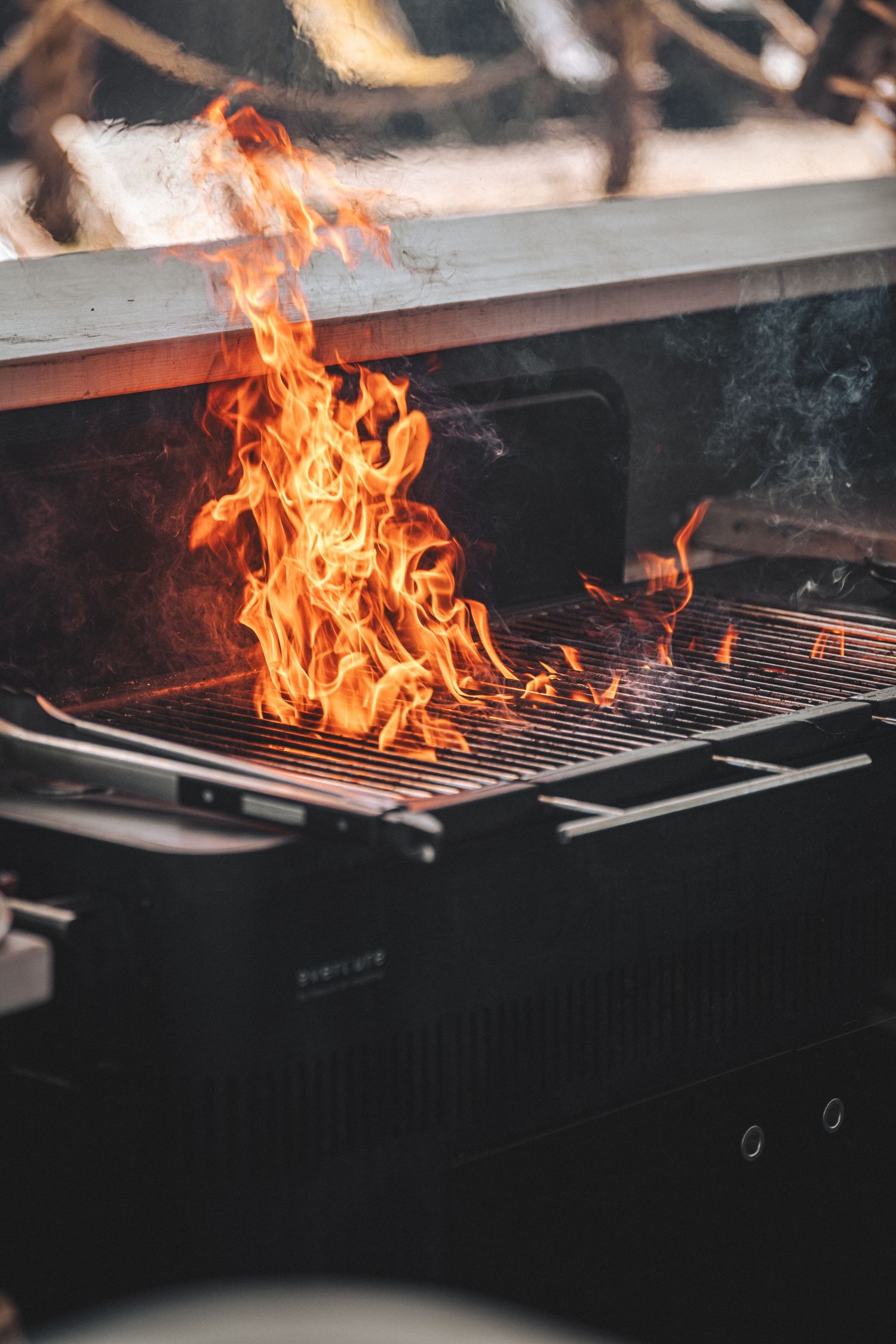 Intense flames rising from a black barbecue grill during outdoor cooking event.