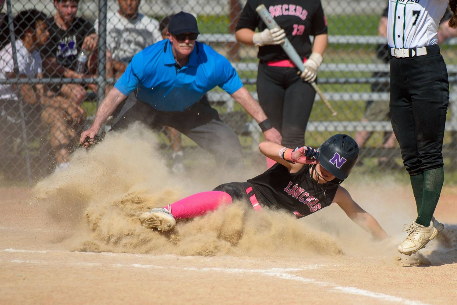 High school softball player sliding into home plate during a game in Massachusetts