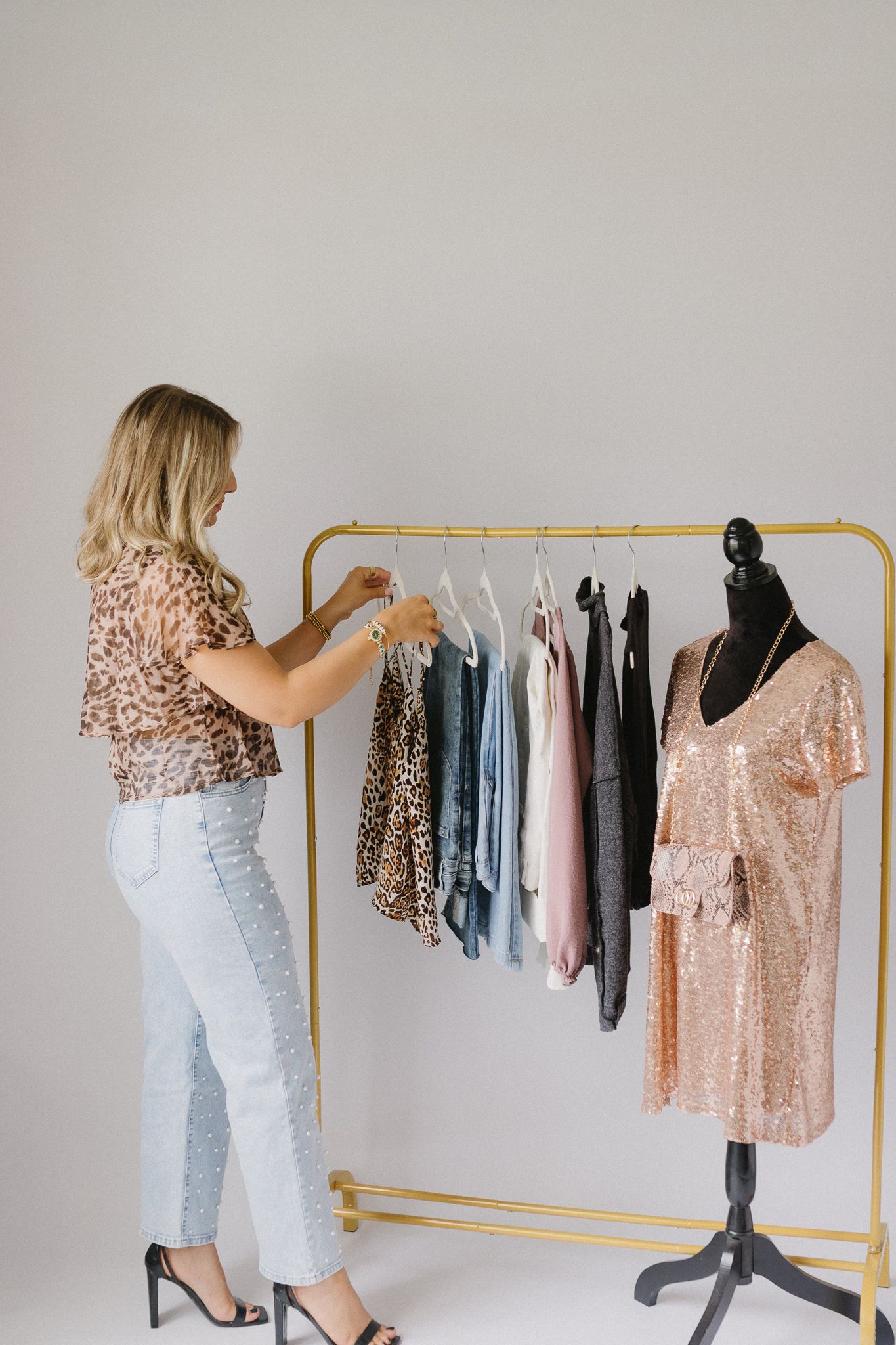 A client of Saylor Heirloom Photography in a professional branding session looking through boutique clothes that their business offers.