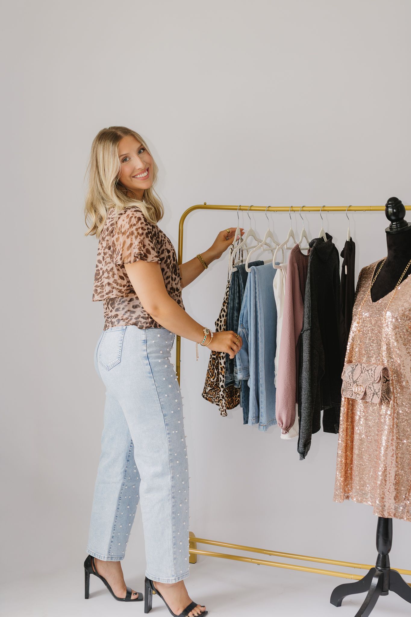 A client of Saylor Heirloom Photography in a professional branding session looking through boutique clothes that their business offers.