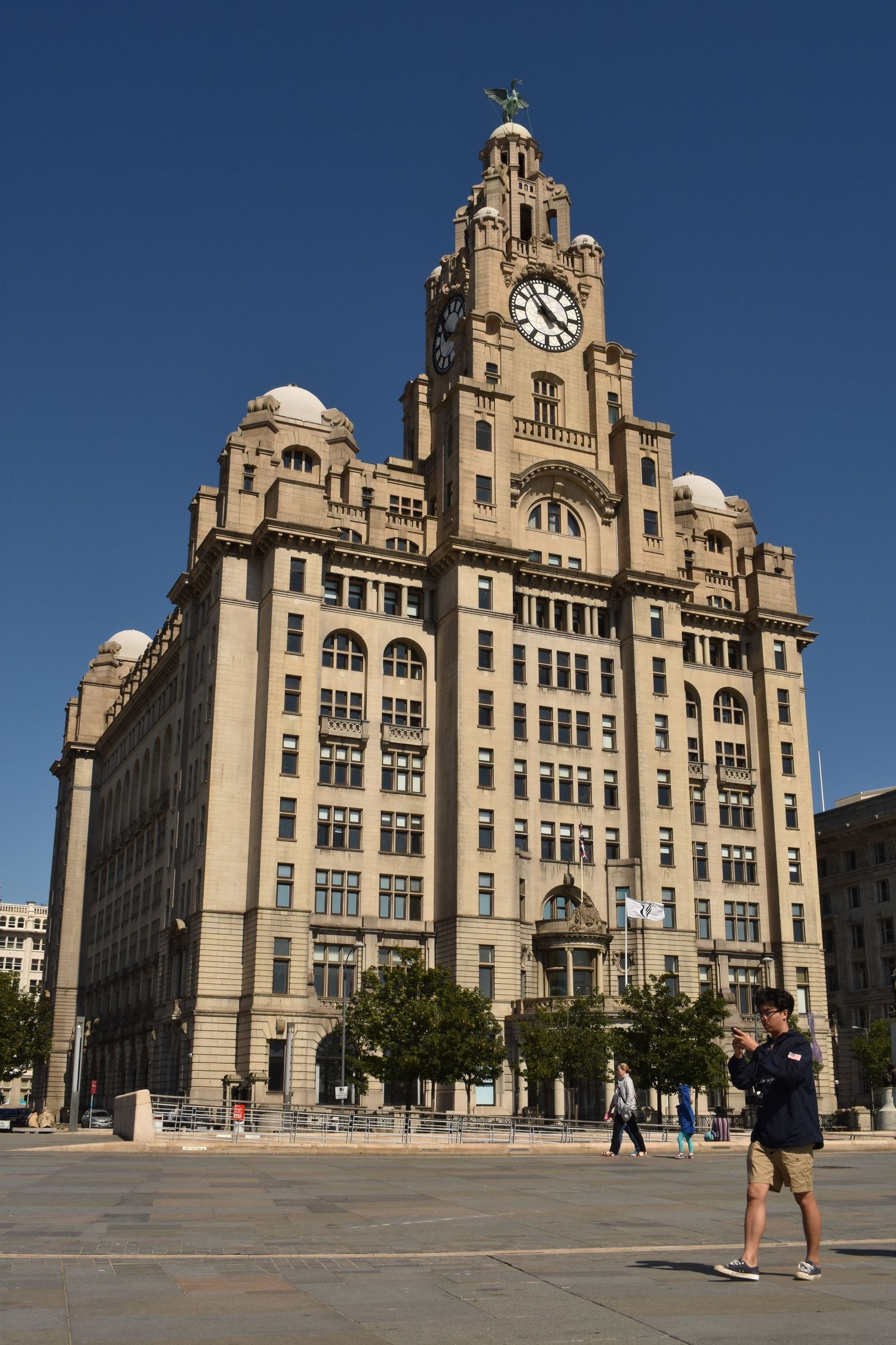 An ornate waterfront building with a tall clock tower beneath a clear blue sky.