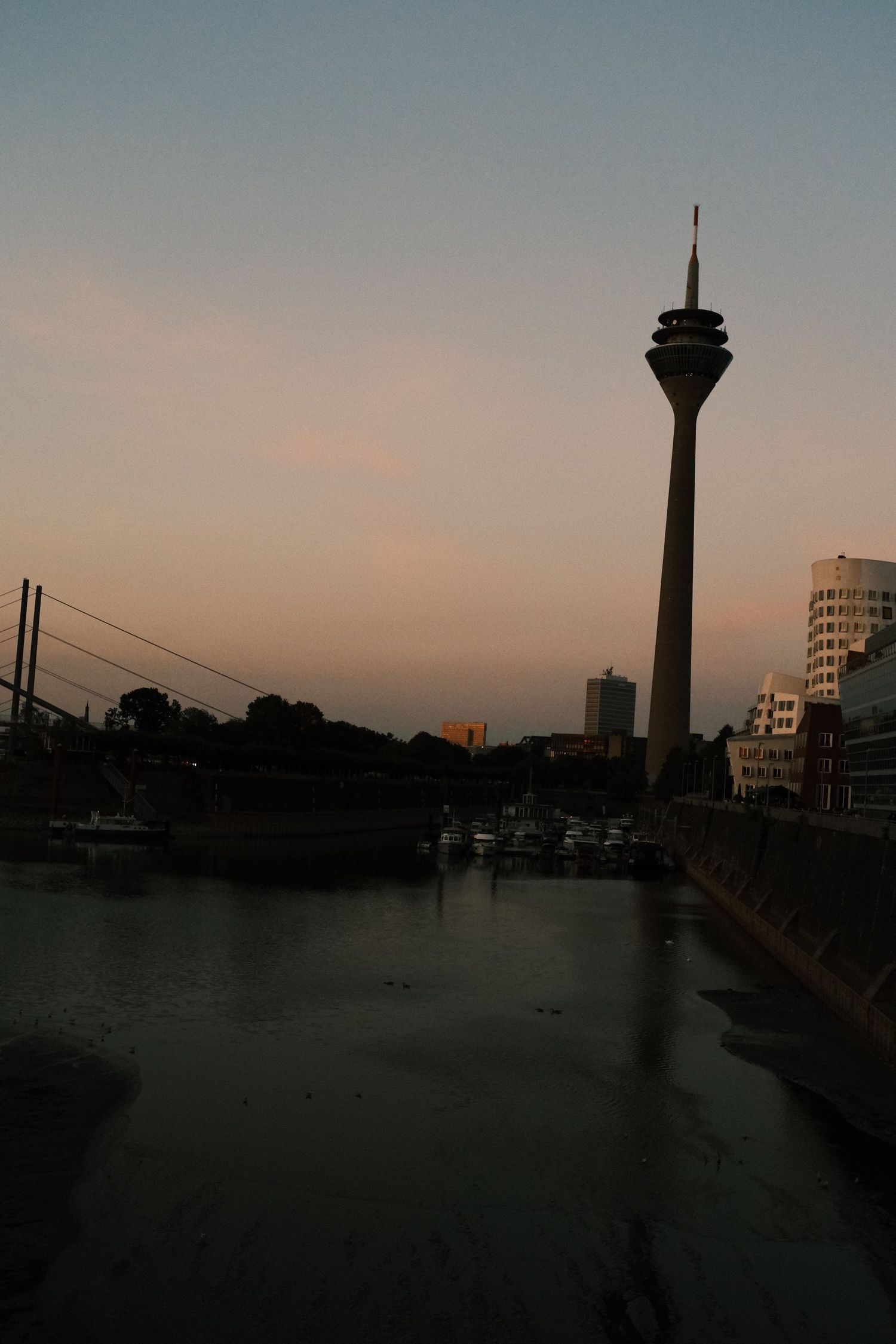 Rheinturm and MedienHafen buildings reflected in the harbour water at dusk, Düsseldorf