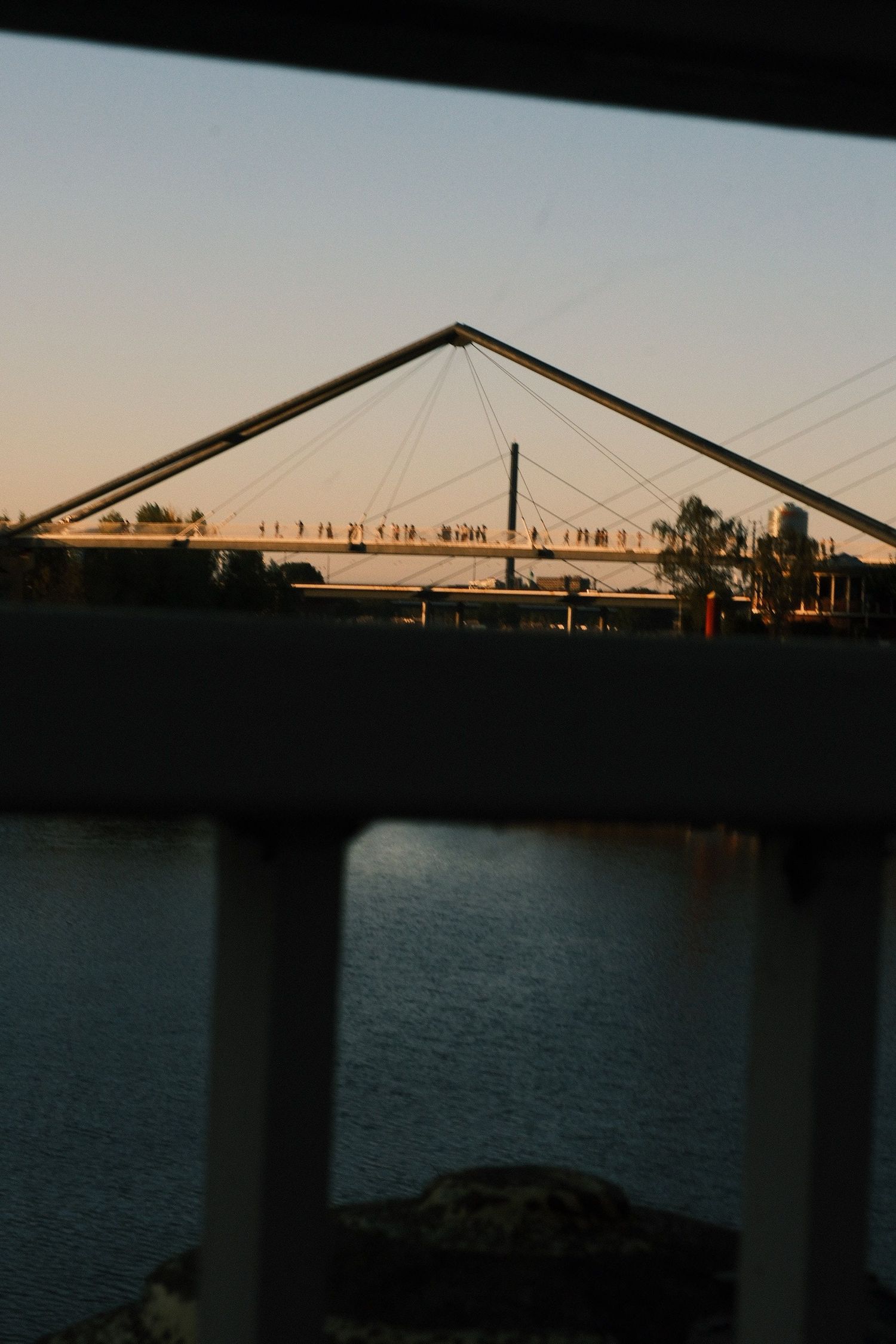 Rhine bridge silhouetted against a warm sunset, framed by a dark underpass in Düsseldorf