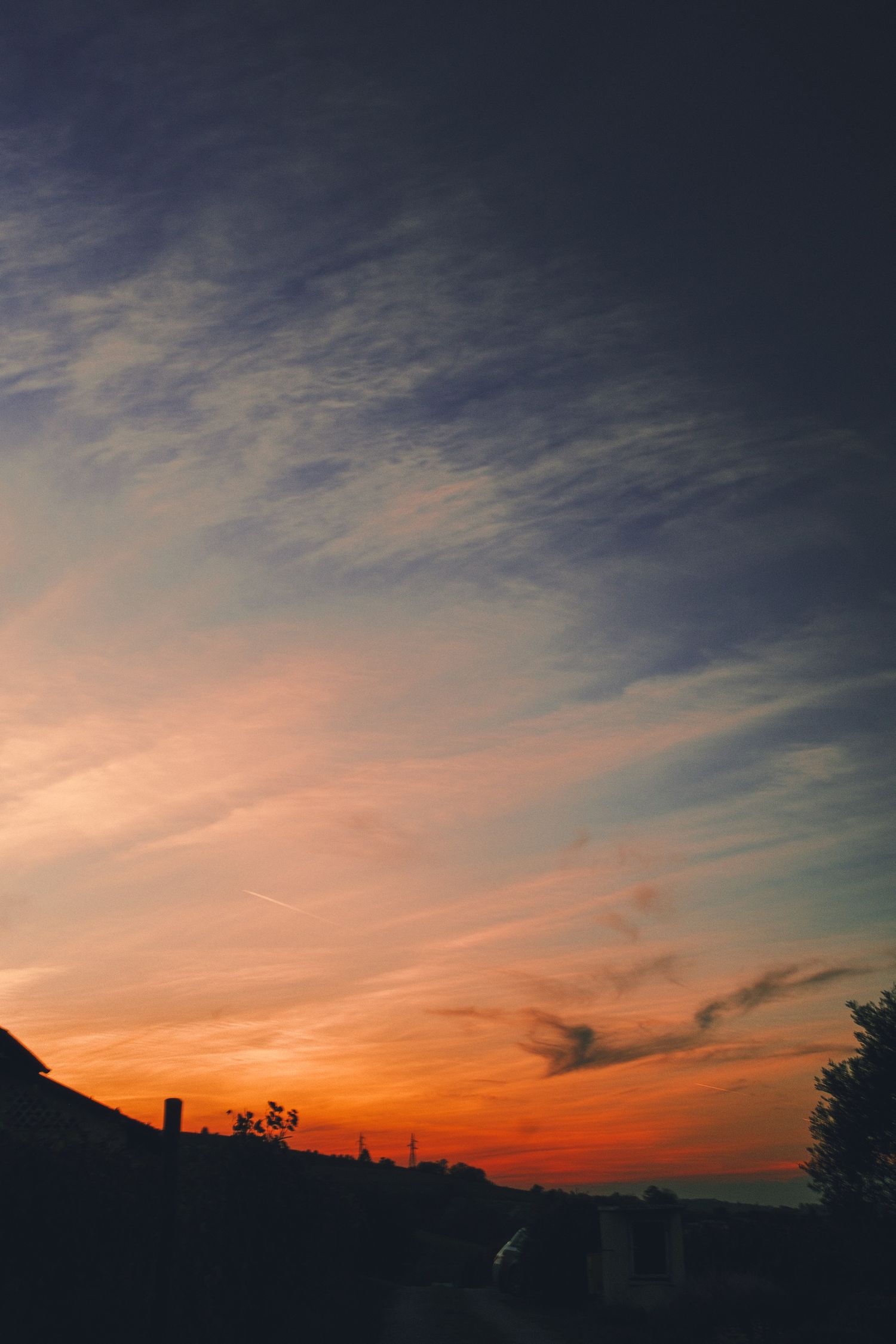 Orange and blue sunset sky over dark silhouetted hills in Piedmont, Italy