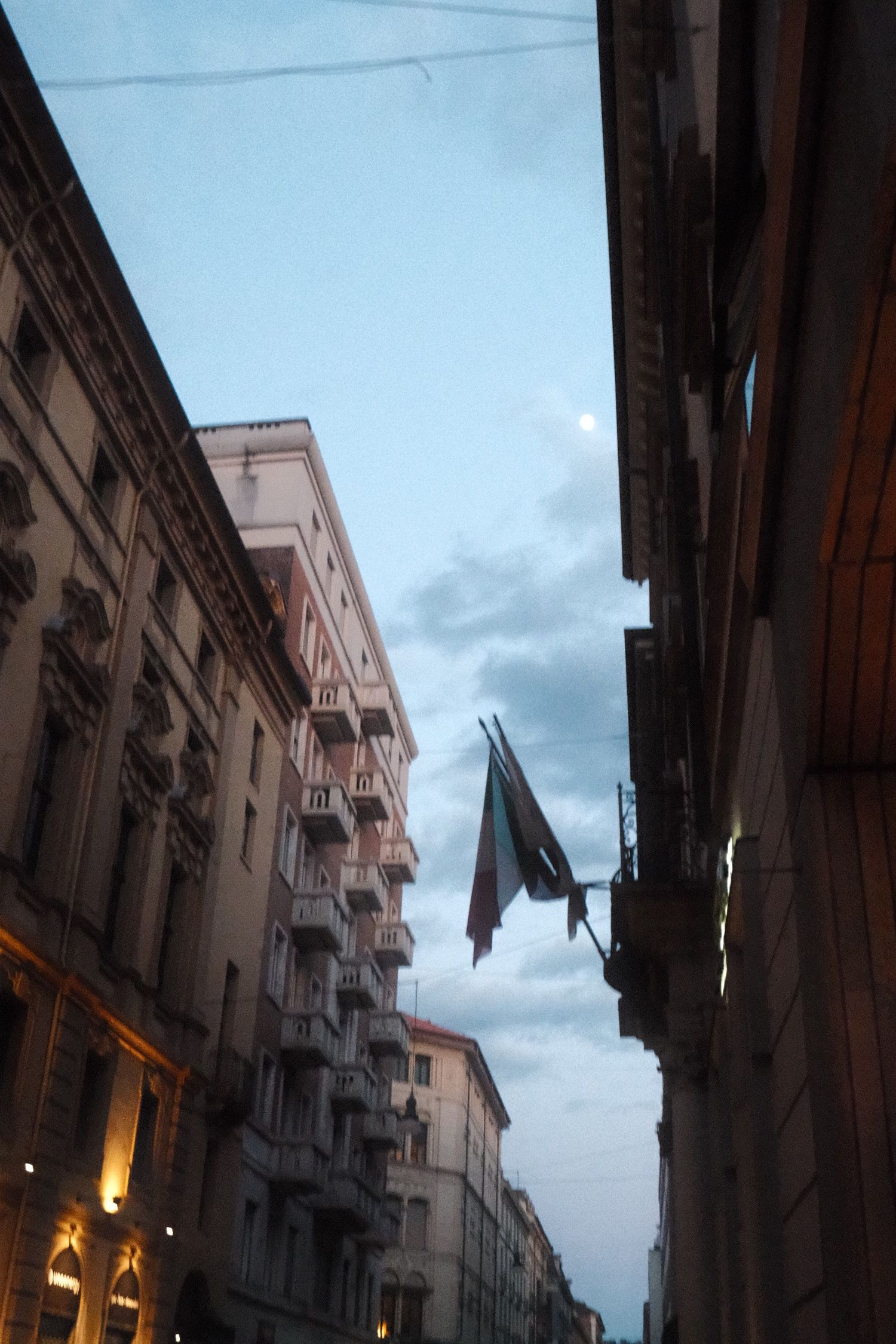 Italian flag hanging over a narrow city street at blue hour