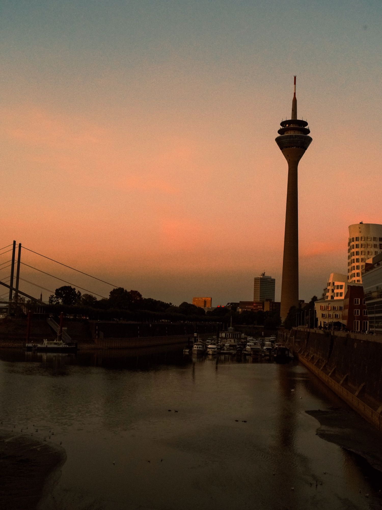 Rheinturm TV tower rising above the Düsseldorf harbour at sunset